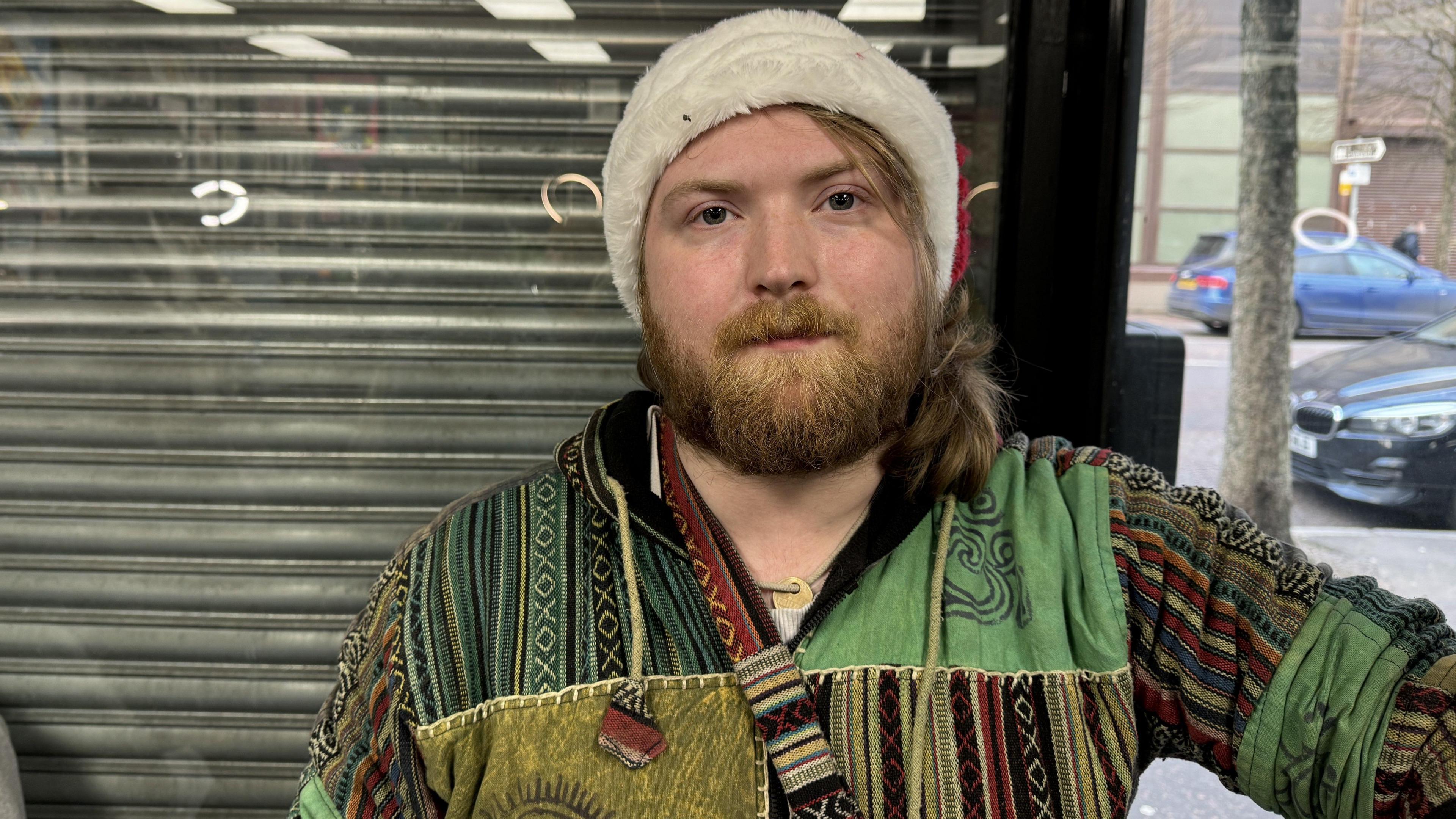 Joshua is wearing a red and white Santa hat, and a green pattern jacket