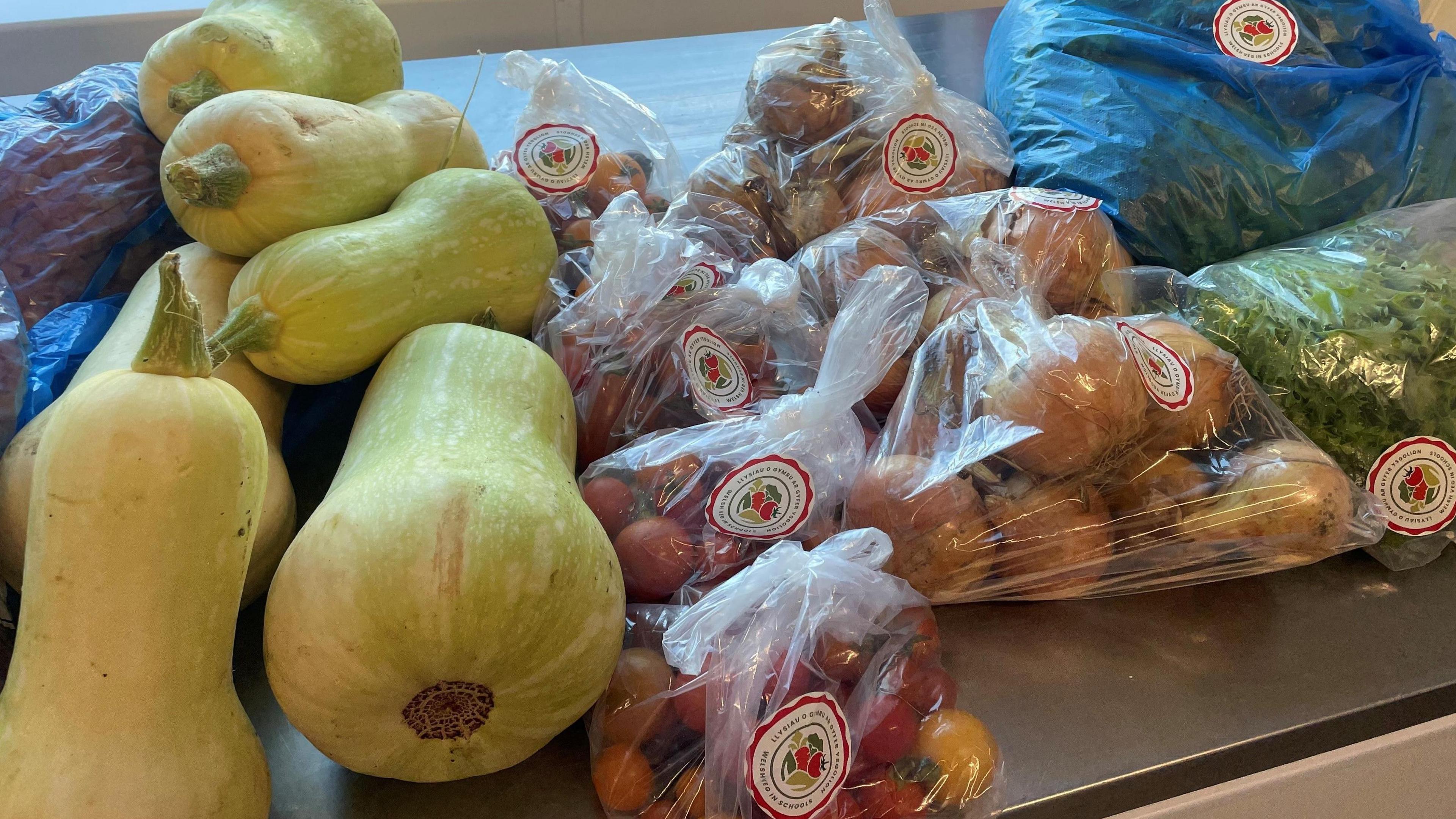 Various veg including onions, tomatos, squash and lettuce displayed on a kitchen counter. 