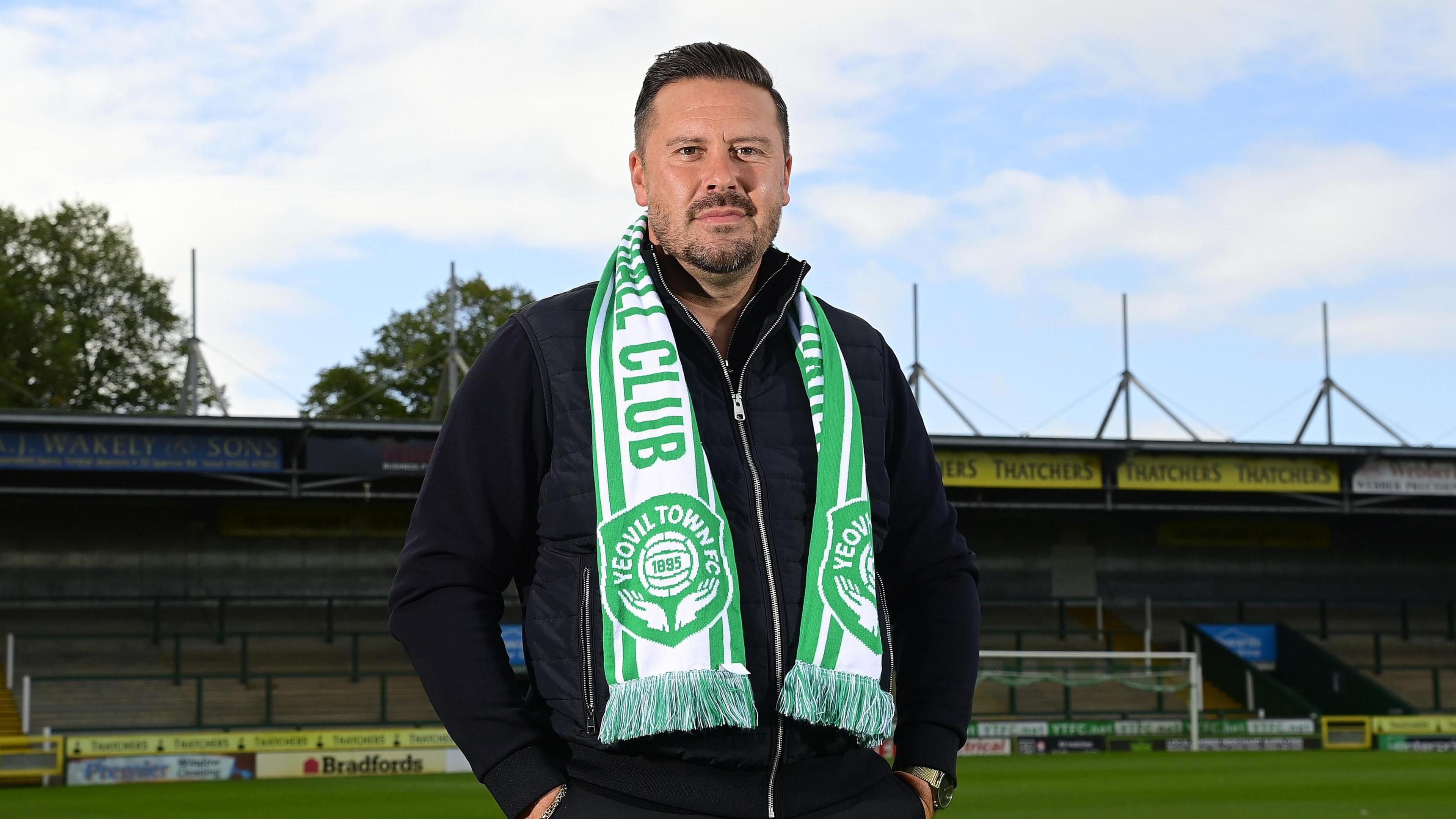 Danny Webb standing at Huish Park with his hands in his pockets and a Yeovil Town scarf around his neck