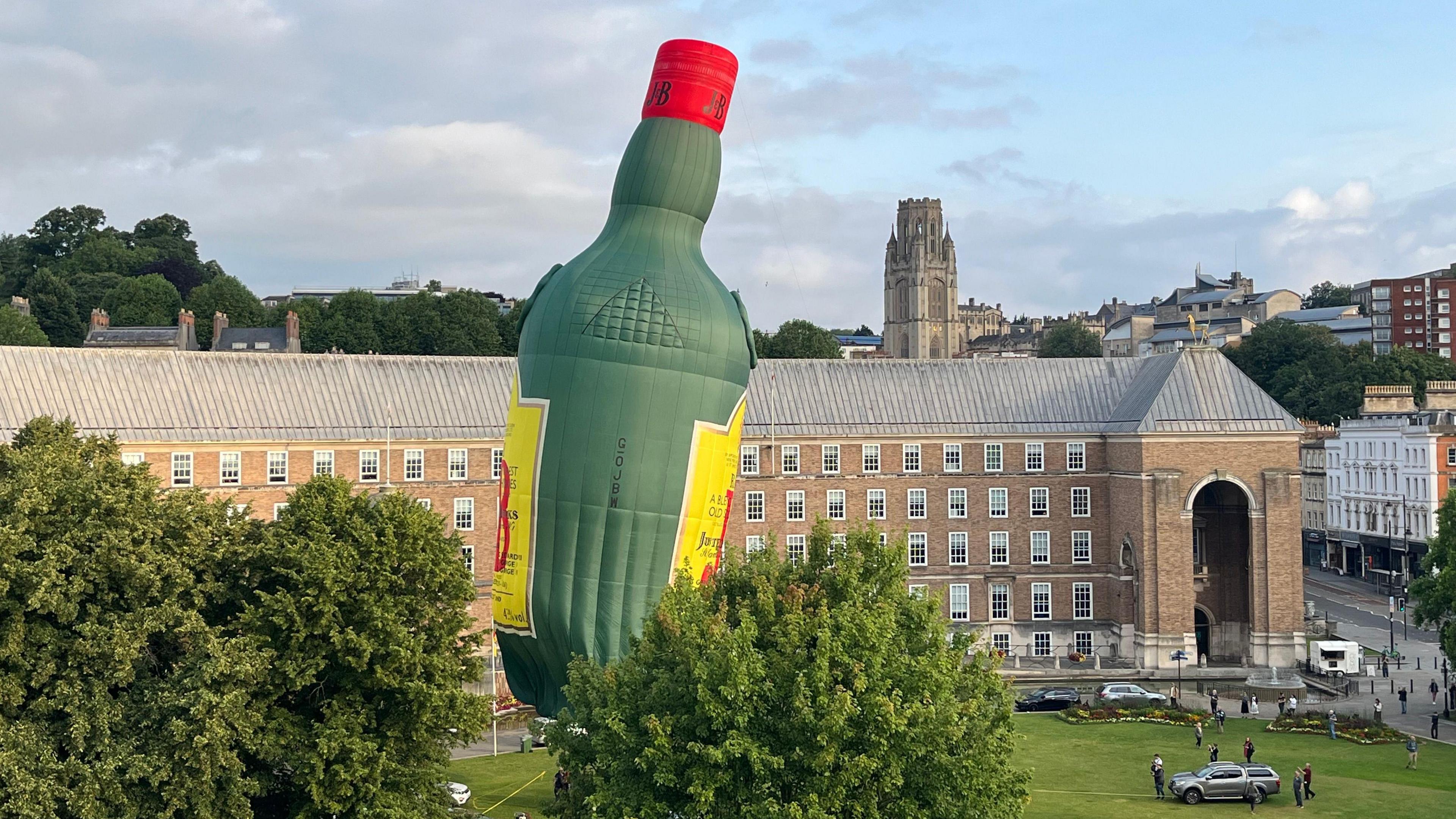 A whiskey bottle shaped hot hair balloon tethered to College Green