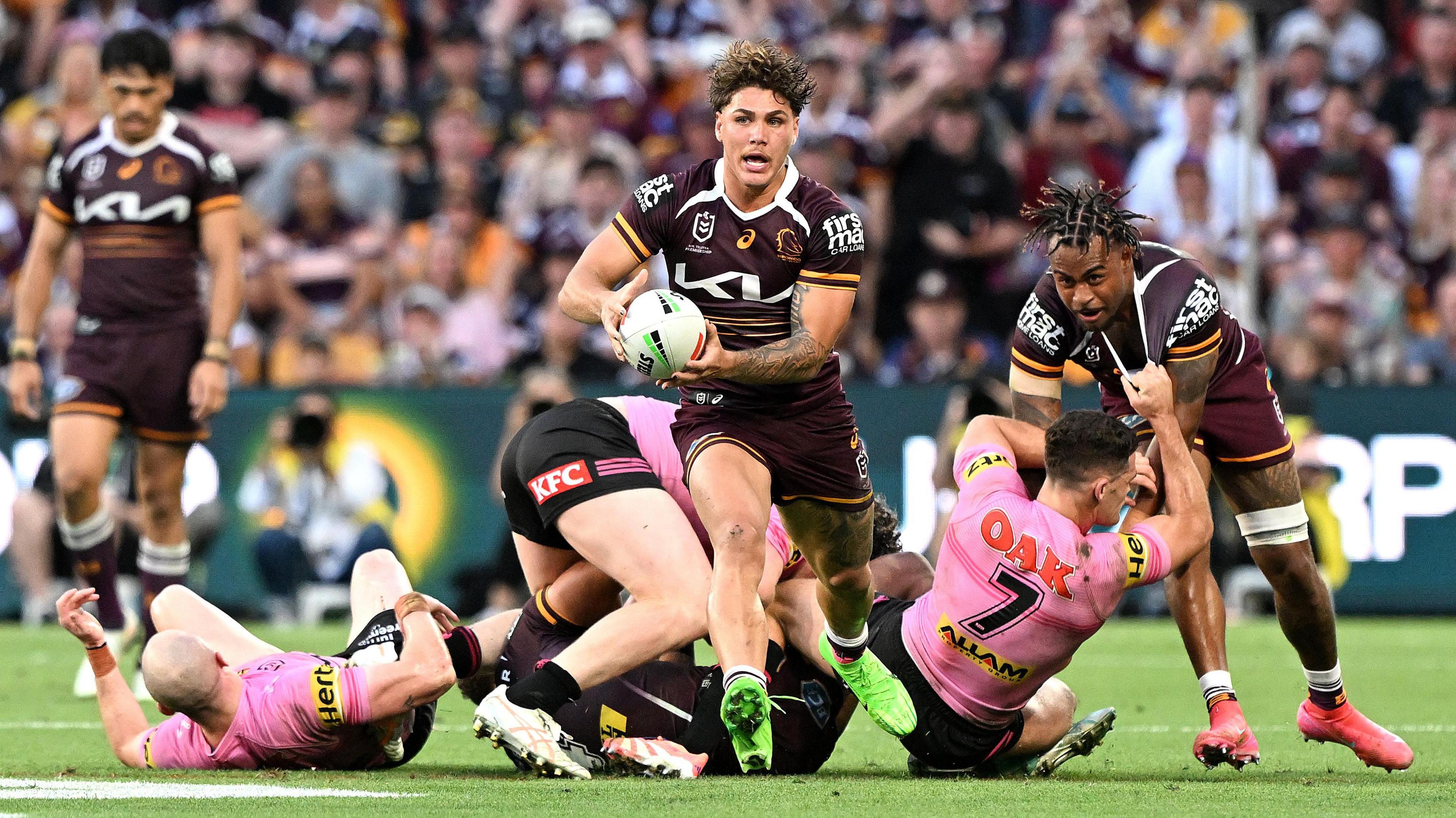 Brisbane Broncos full-back Reece Walsh breaks clear of the pack as Penrith fail to tackle him as he pushes up with the ball in his hand, leaving several players grasping at air in his wake.