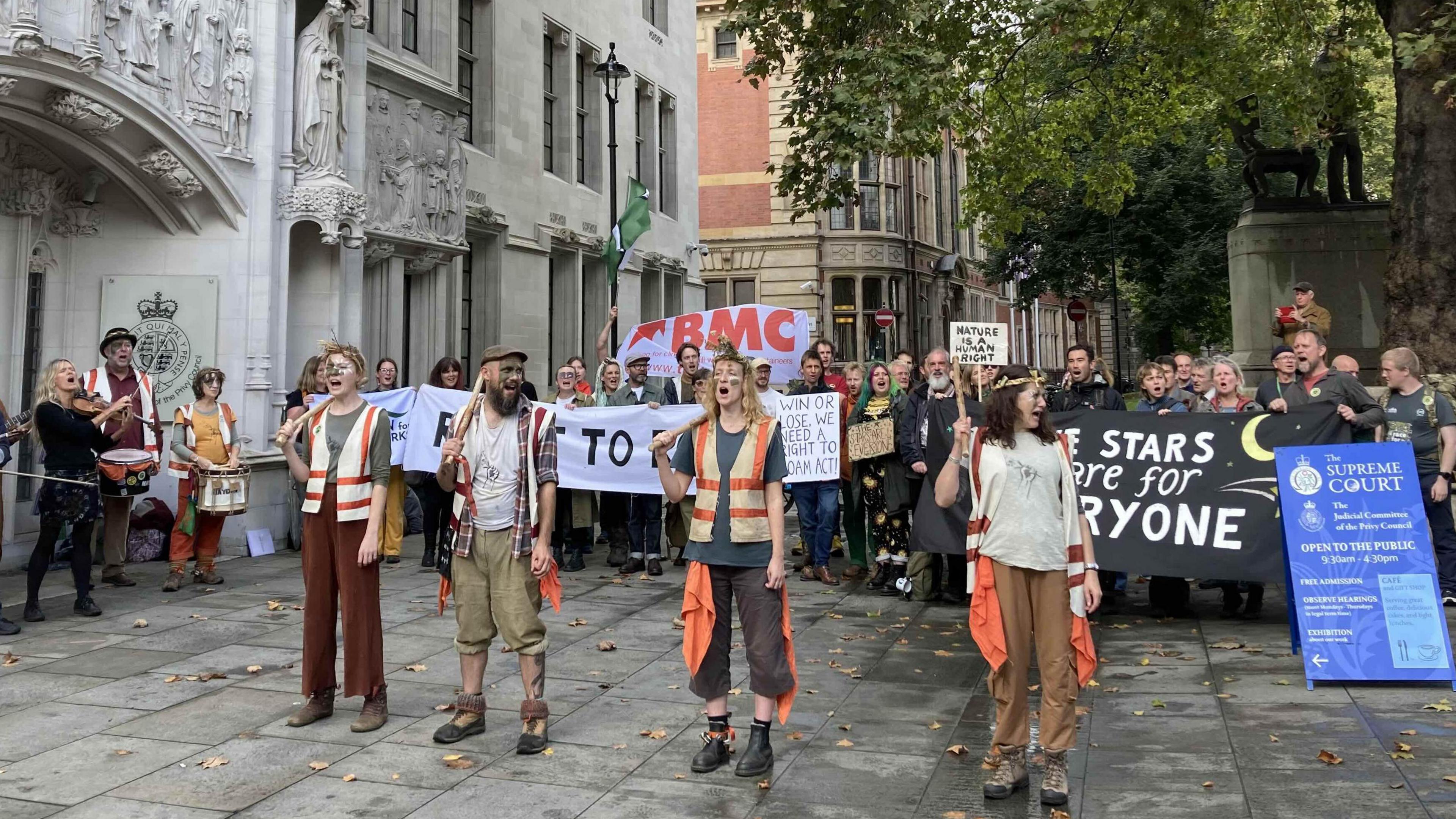 A number of people holding banners and placards outside the Supreme Court in London.