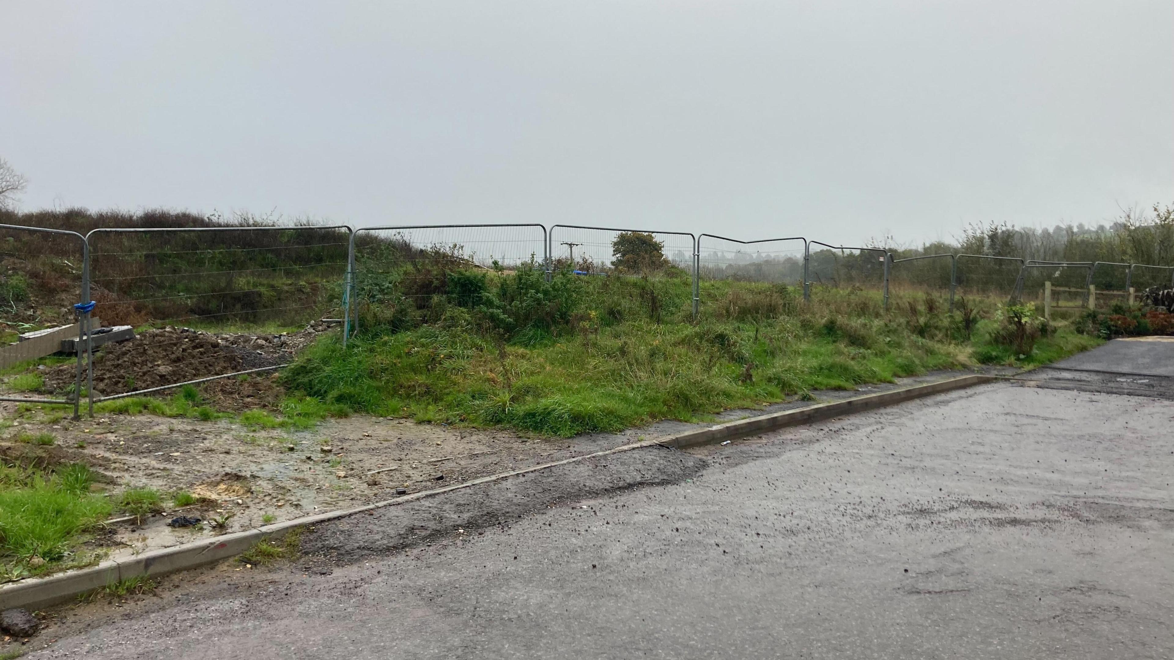 A fence separating the residential development that is being built and the land the developer wants to build