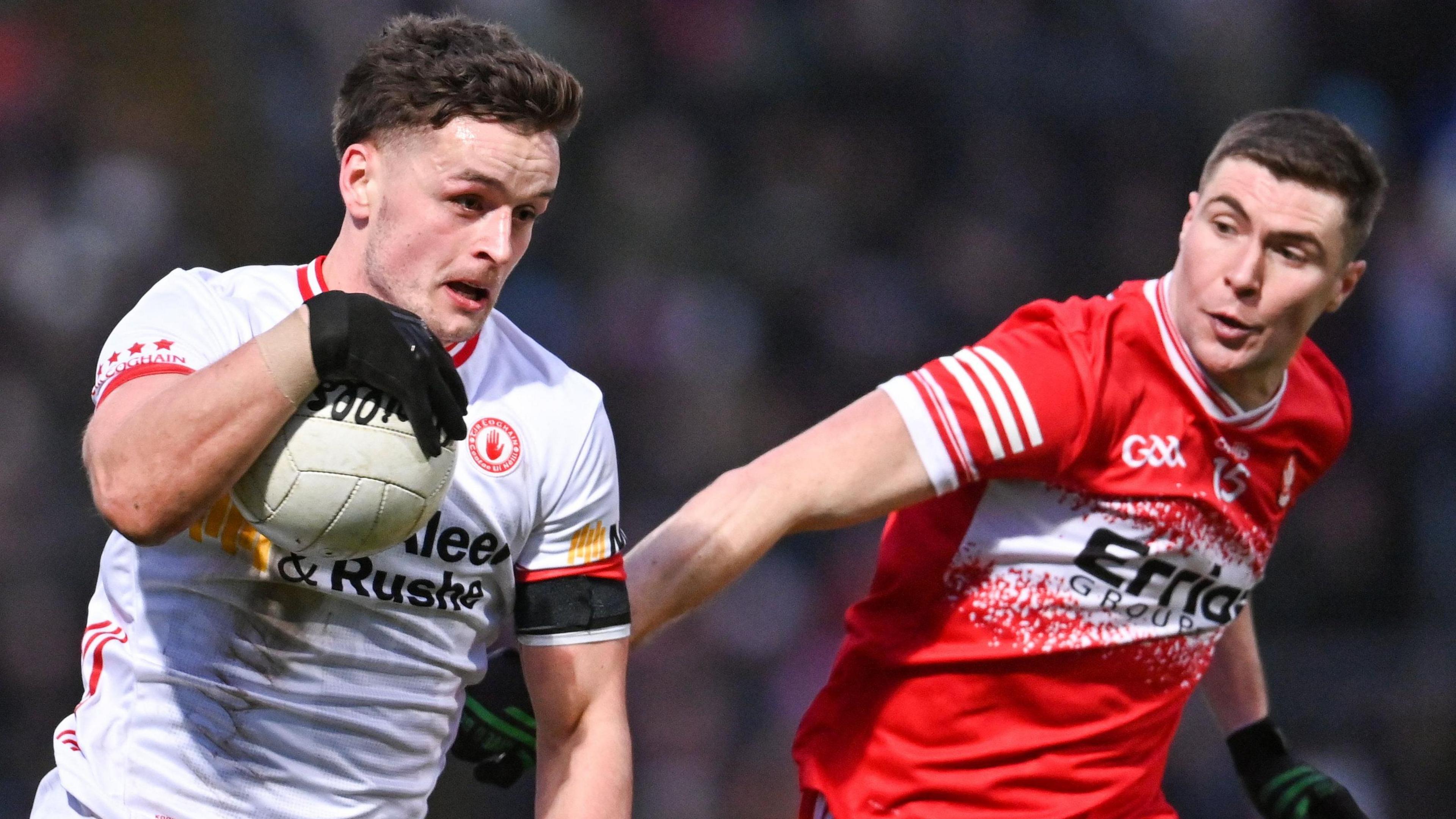 Tyrone's Michael McKernan runs past Derry's Ciaran McFaul with the ball 