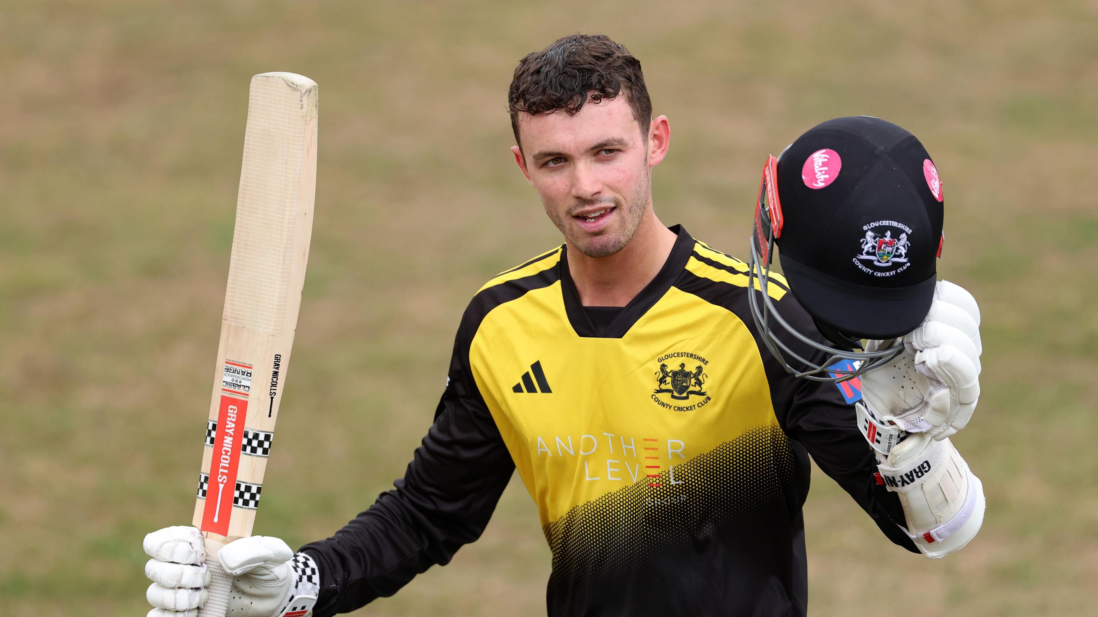 Ollie Price raises his bat in one hand and his helmet in the other to acknowledge his century at Cheltenham
