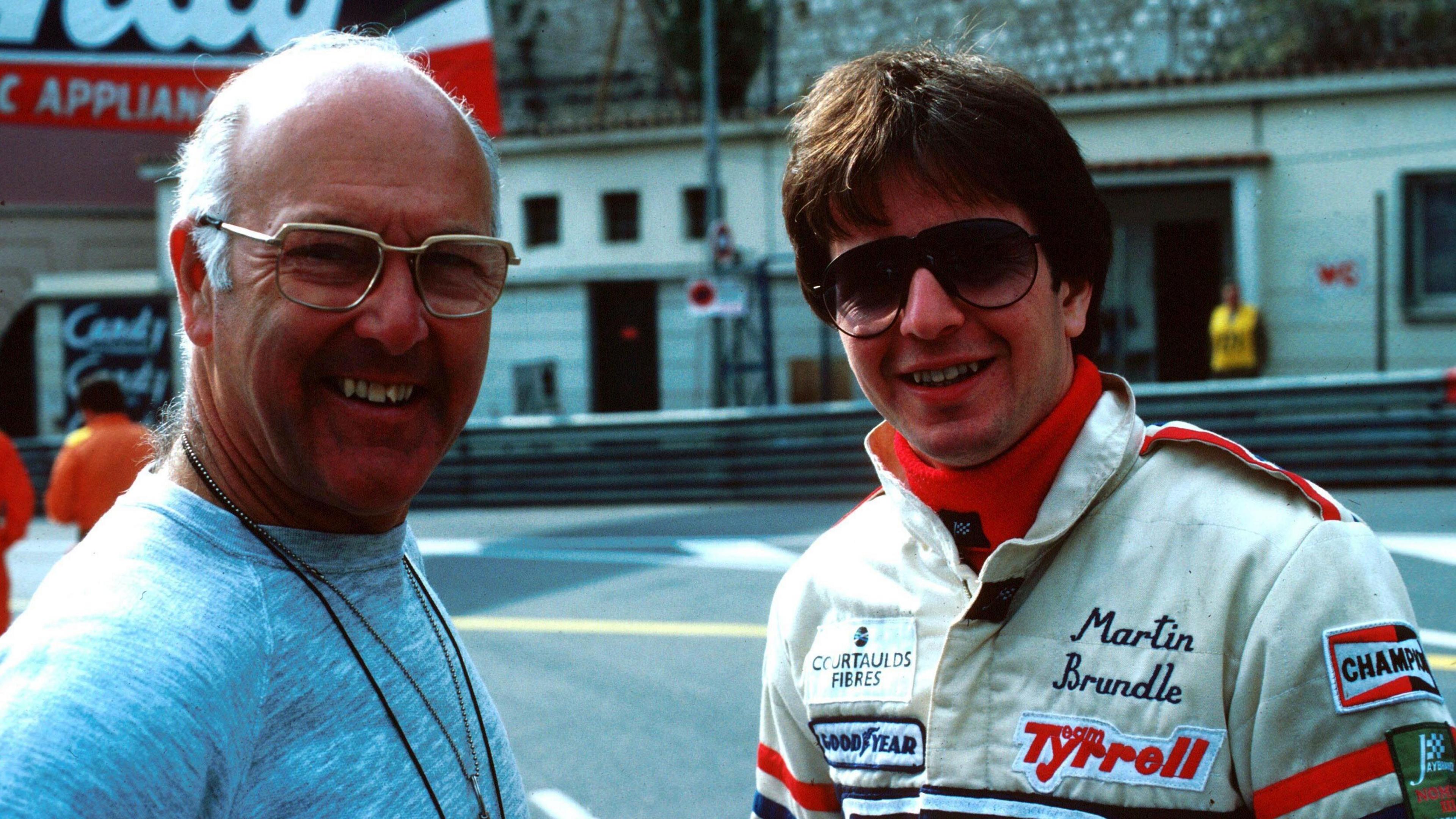 Murray Walker and Tyrrell's Martin Brundle, wearing sunglasses, smile while posing for a picture in 1985