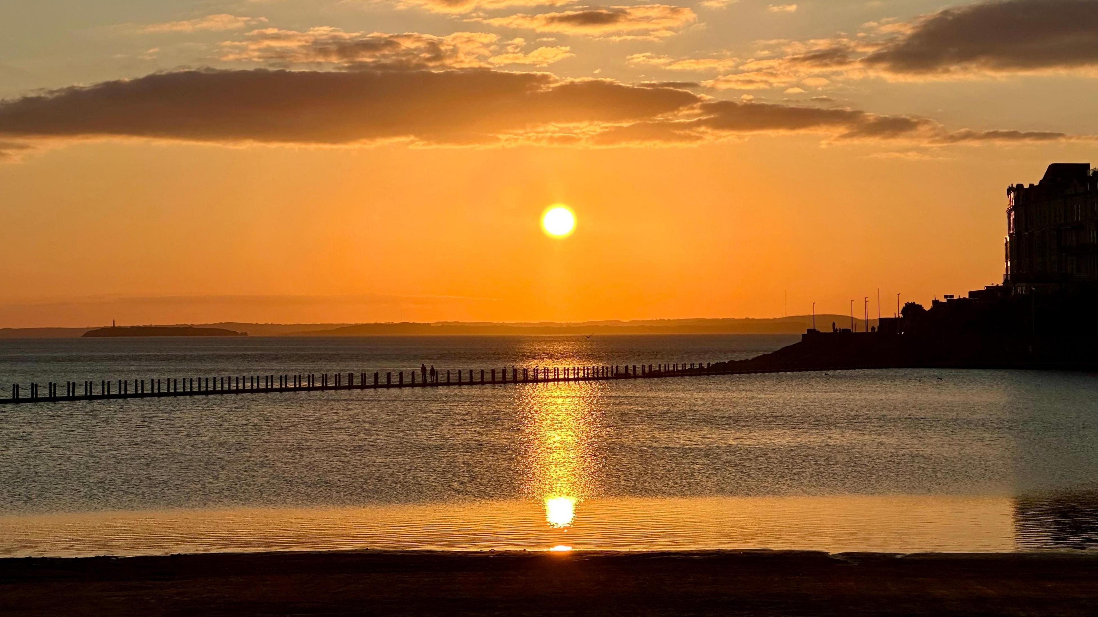 The sun sets over the sea at Weston super Mare and turns the sky orange.