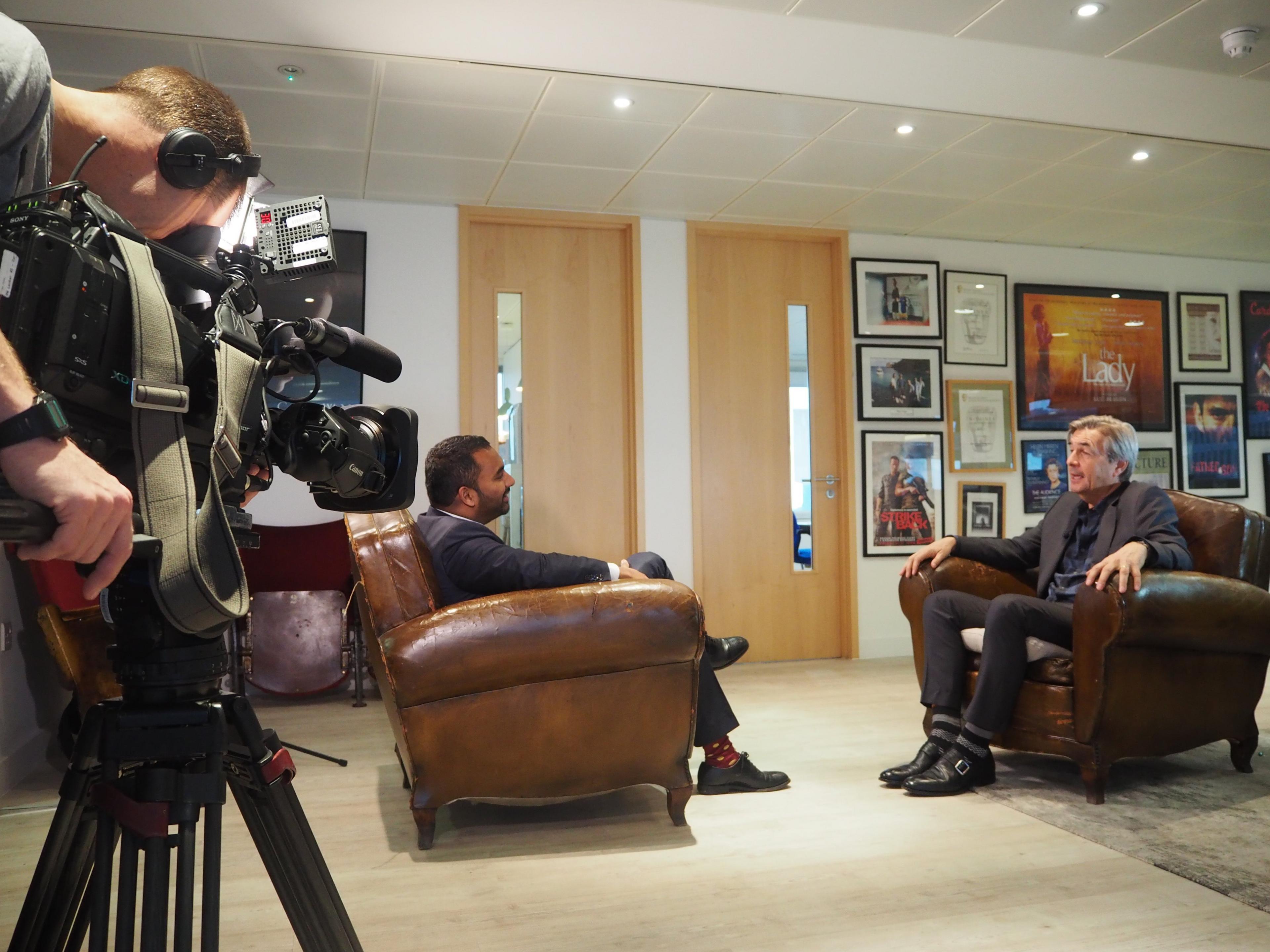 BBC cameraman Carl Ward films with Amol Rajan at the offices of The Crown's executive producer Andy Harries