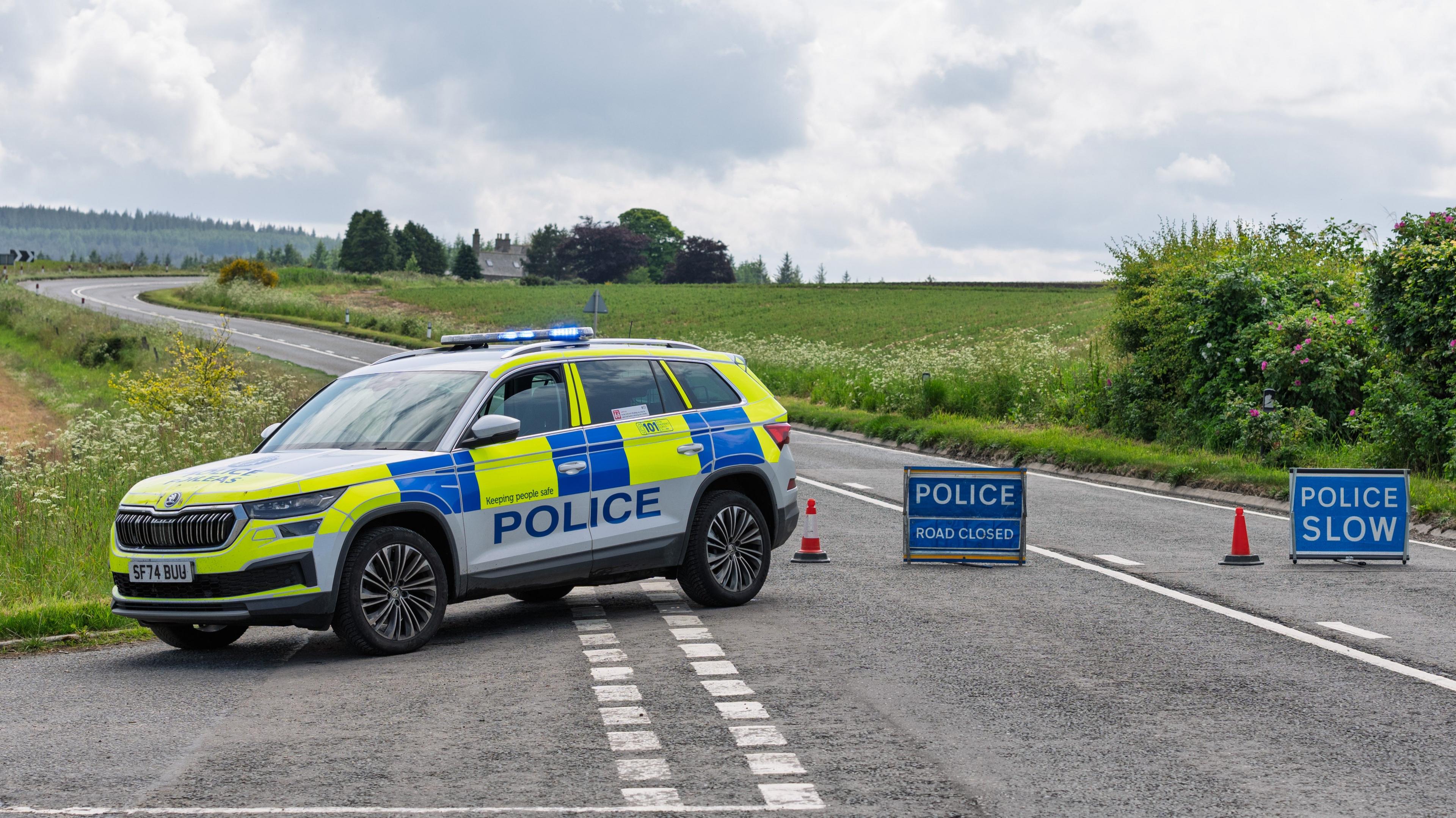 Police car next to 'police accident' signs on a rural road.