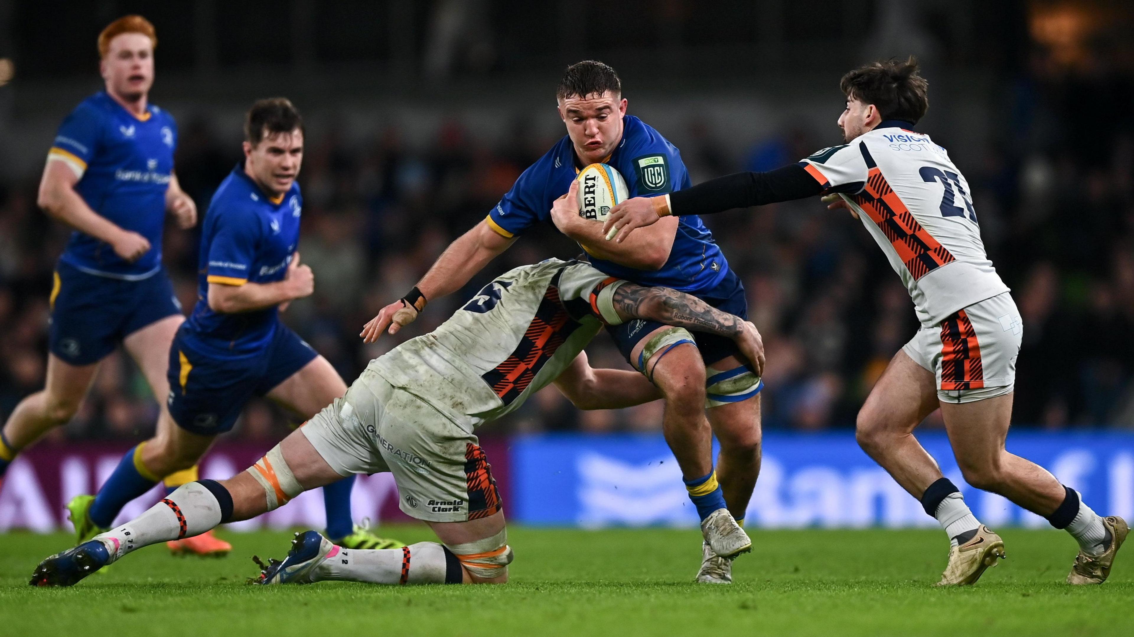Scott Penny is tackled by Glen Young, left, and Charlie Shiel of Edinburgh during the United Rugby Championship match between Leinster and Edinburgh