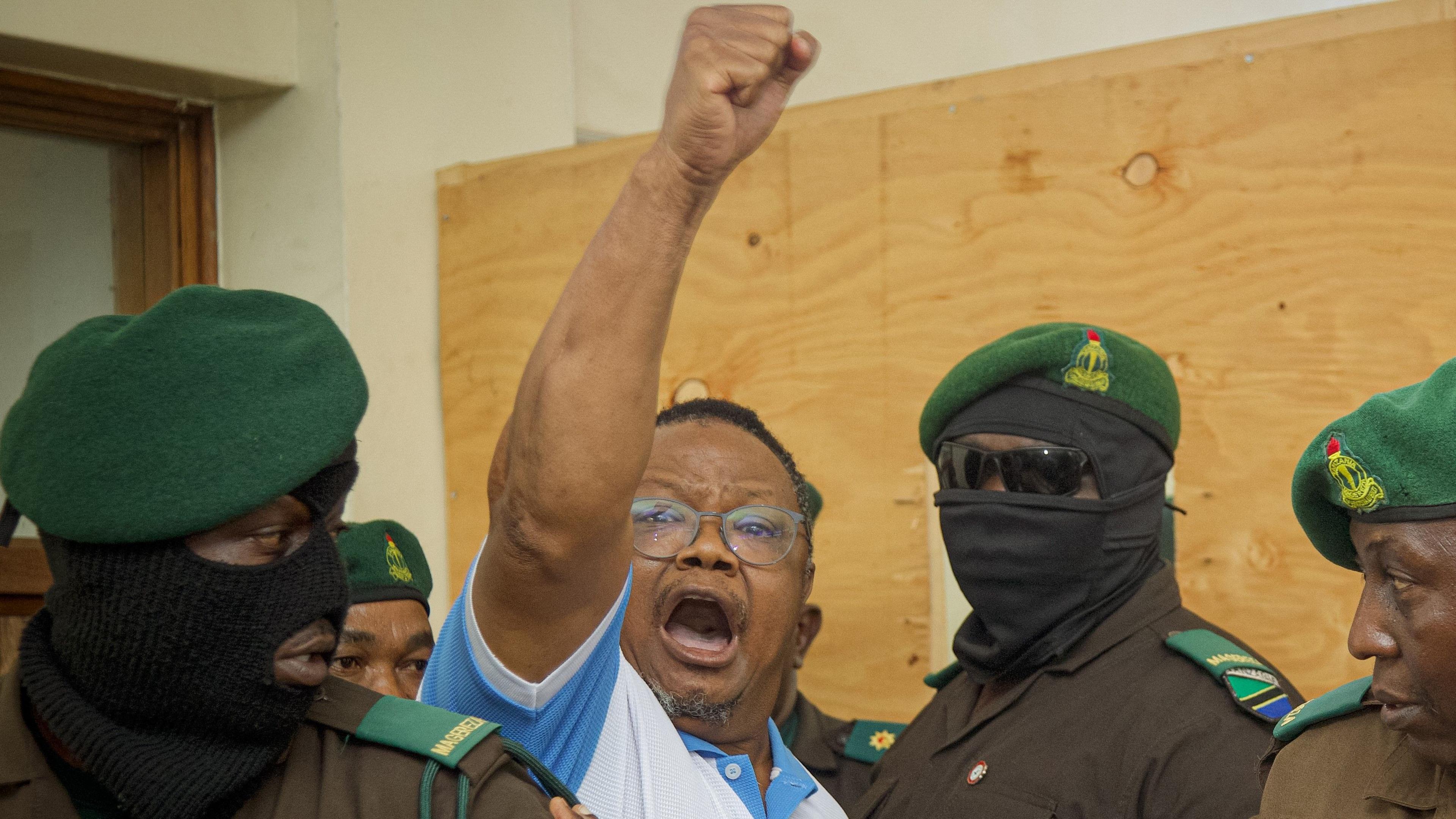 Tanzania's main opposition leader Tundu Lissu (2nd L) raises his fist in the air as he enters the court room at Kisutu magistrate's court in Dar es Salaam. He is surrounded by security officers in uniform, some with face masks