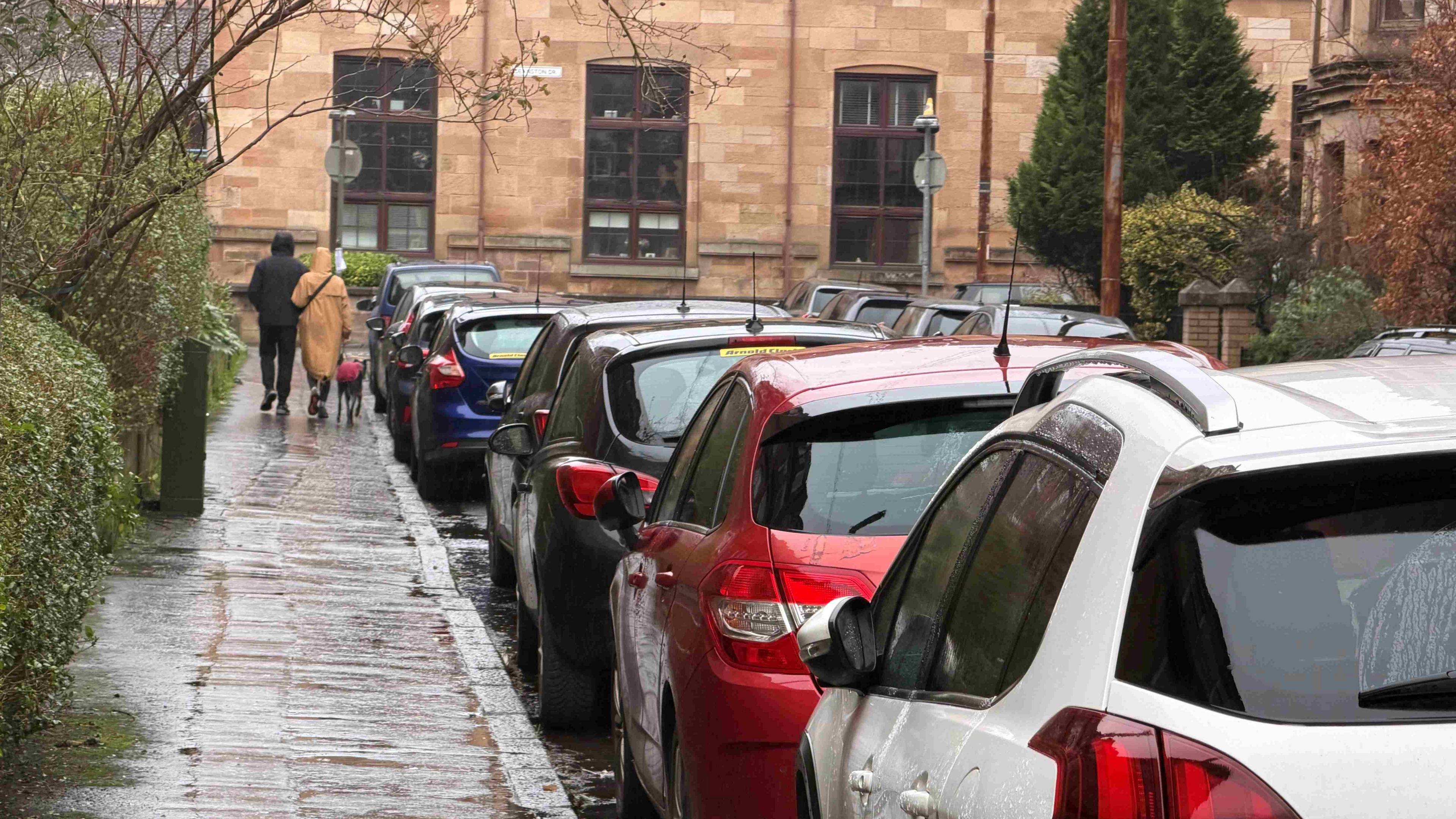 A busy residential street with parked cars along both sides.