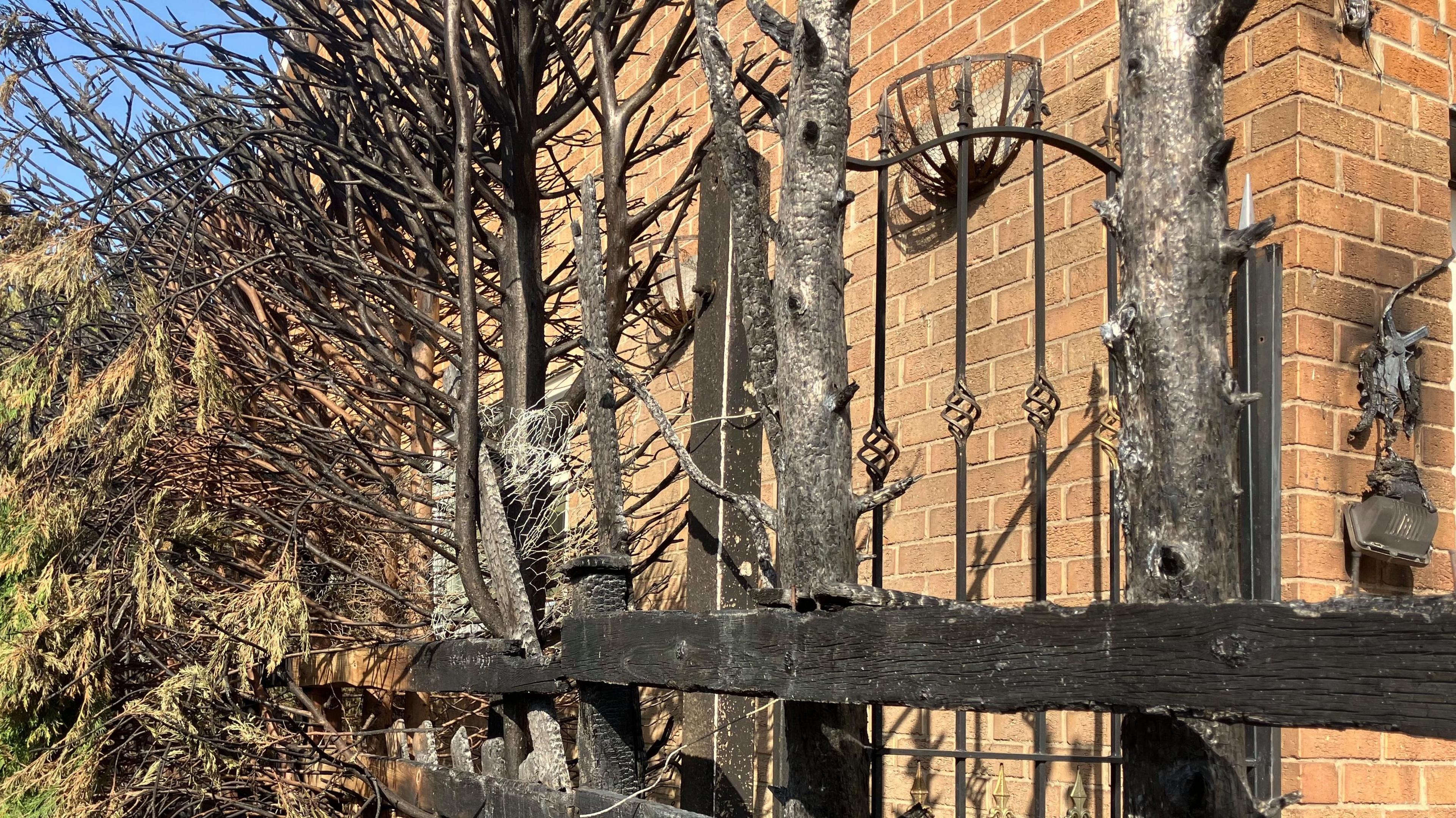 Burnt fence and melted bits of furnishing are pictured
