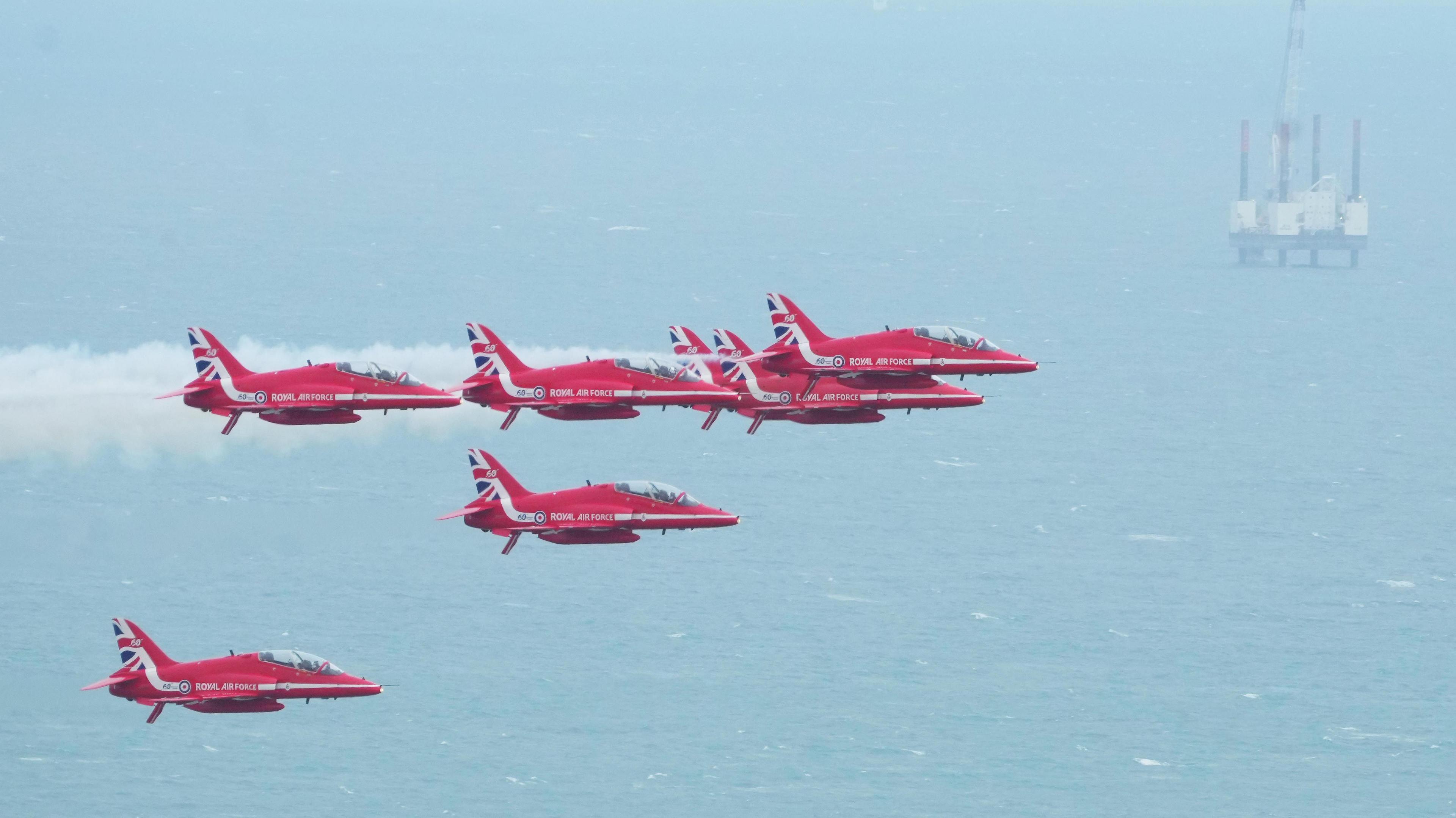 Red planes fly with the sea visible in the background