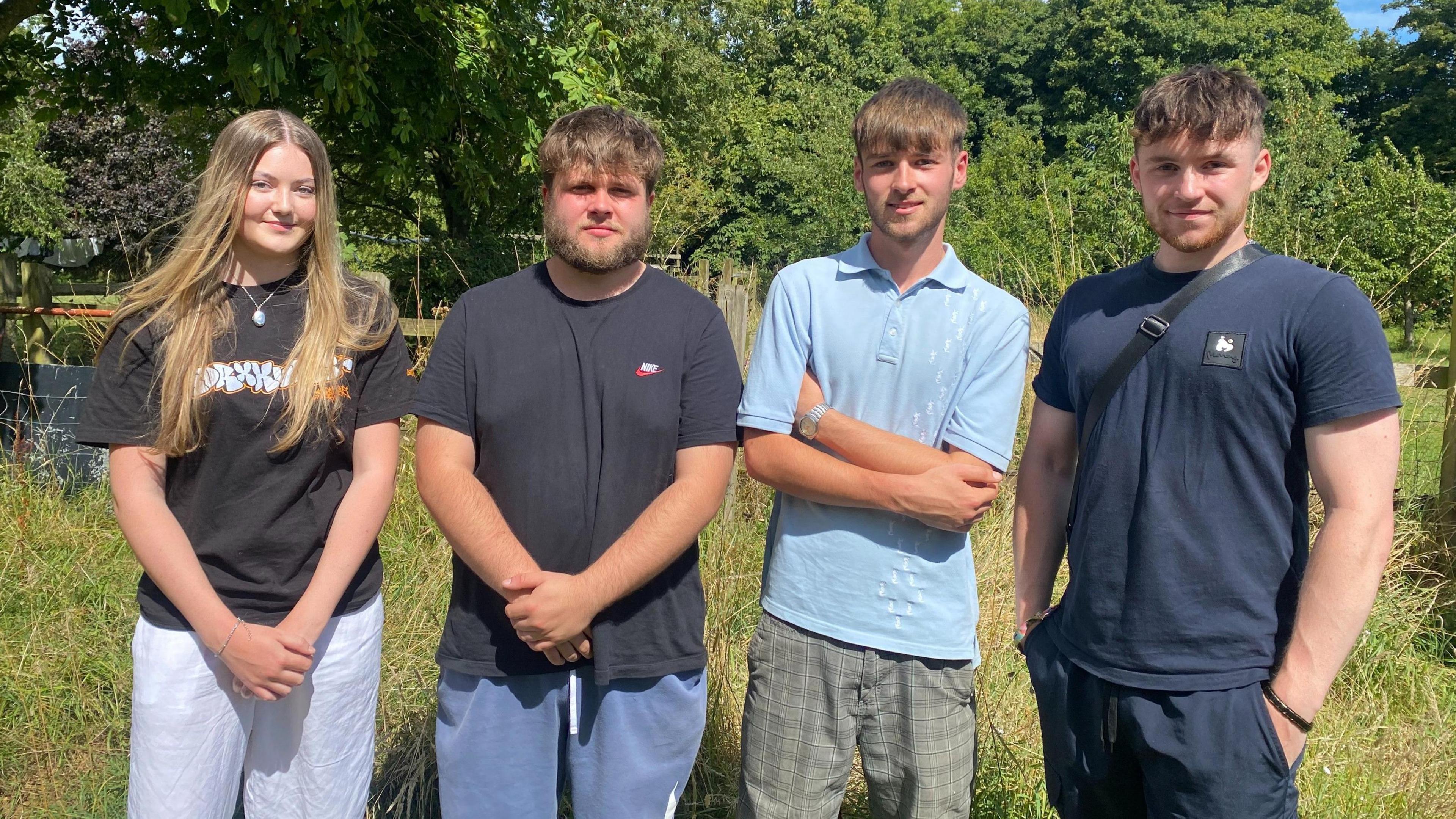 Darcey Leighton and friends Olly Ley, Jacob Clements and Callum Whiting in the family's garden. The four are standing side by side in a line and are looking at the camera. 