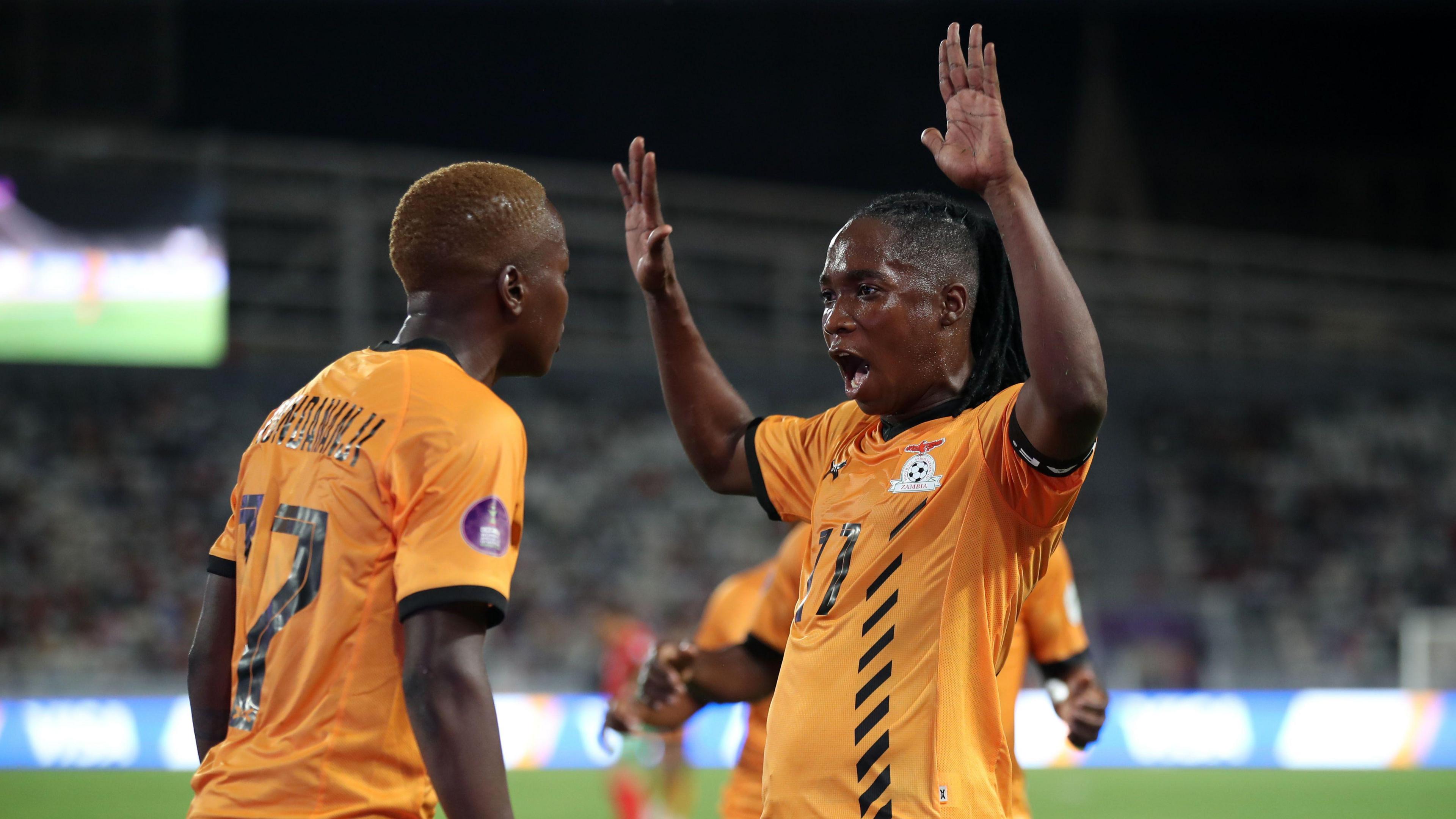 Zambia skipper Barbra Banda raises some hands successful nan aerial arsenic she celebrates a extremity pinch team-mate Racheal Kundananji