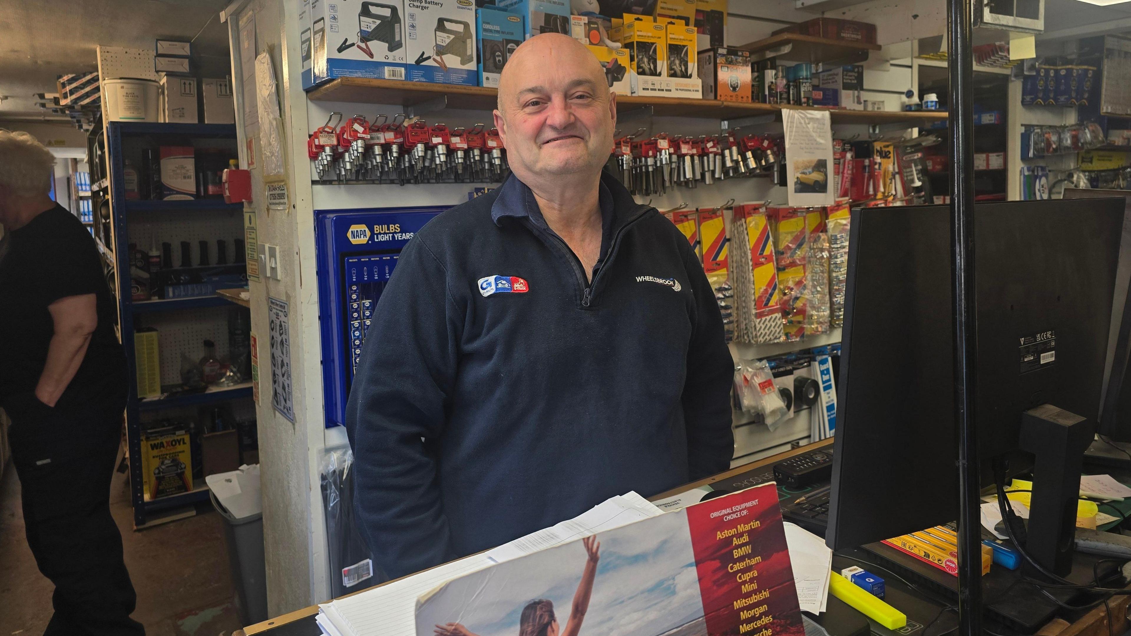 Marcus Thackray, from Wheelsbrook Services in Holmfirth, stood behind a counter wearing a dark blue jumper with the company's logo