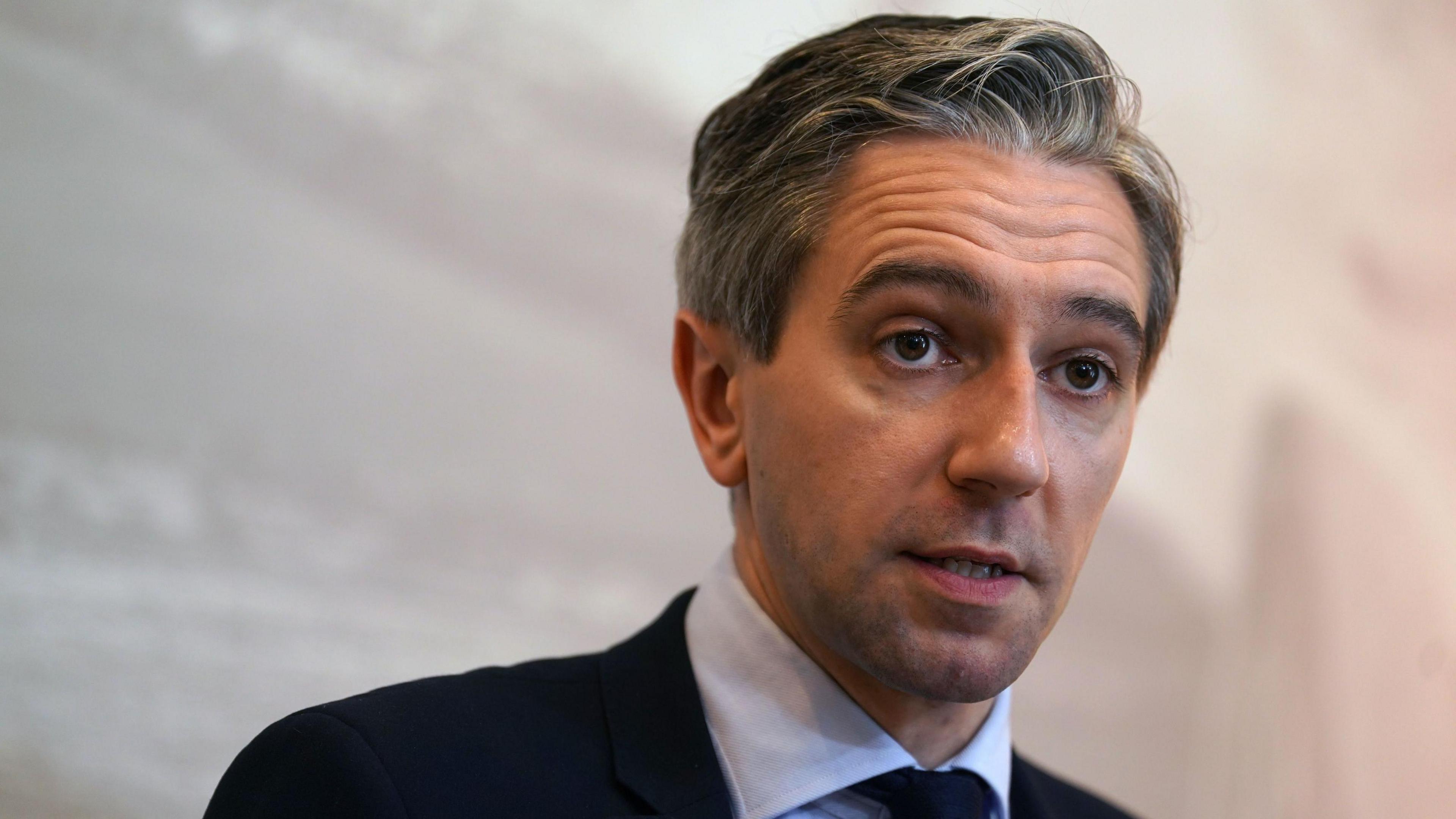 Simon Harris, who has grey hair and a navy suit, with navy tie and light blue shirt 