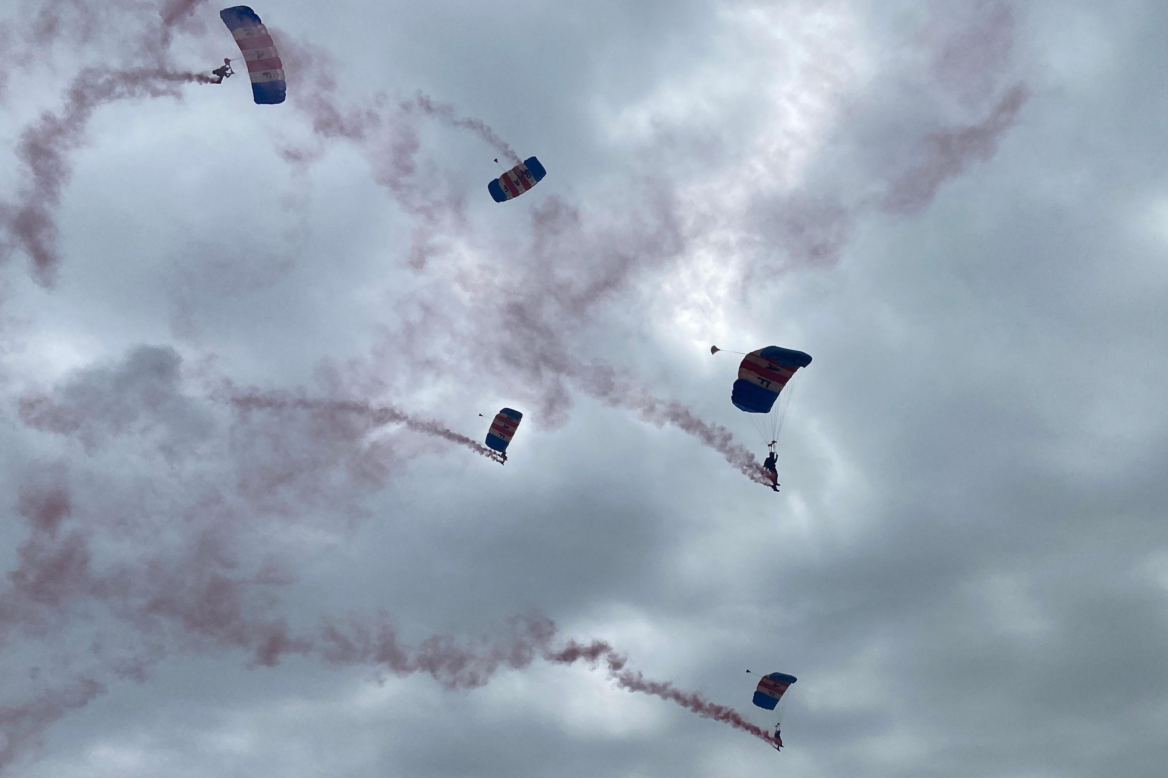 Five members of the RAF Falcons parachuting with smoke trailing behind them