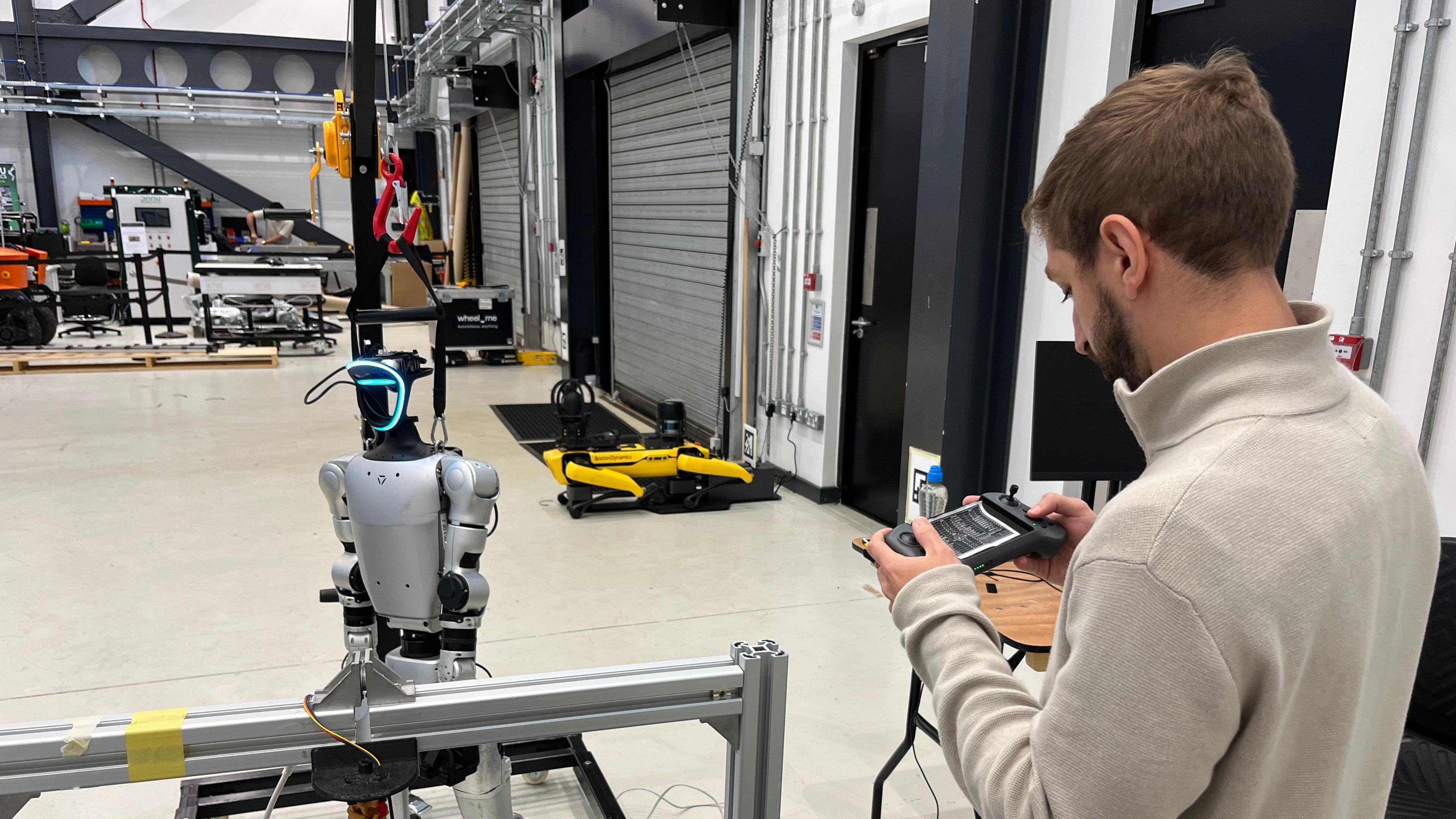 A robotic engineer is working with a prototype of a humanoid robot in a large laboratory at Heriot Watt University