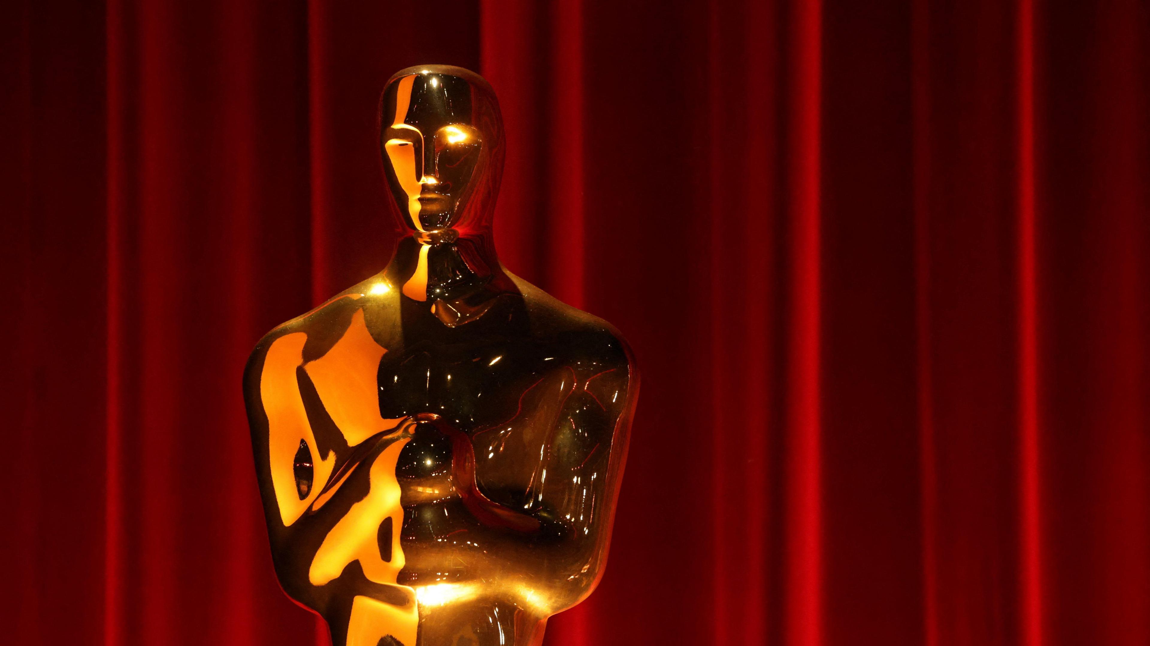 An Oscar trophy in front of a red curtain
