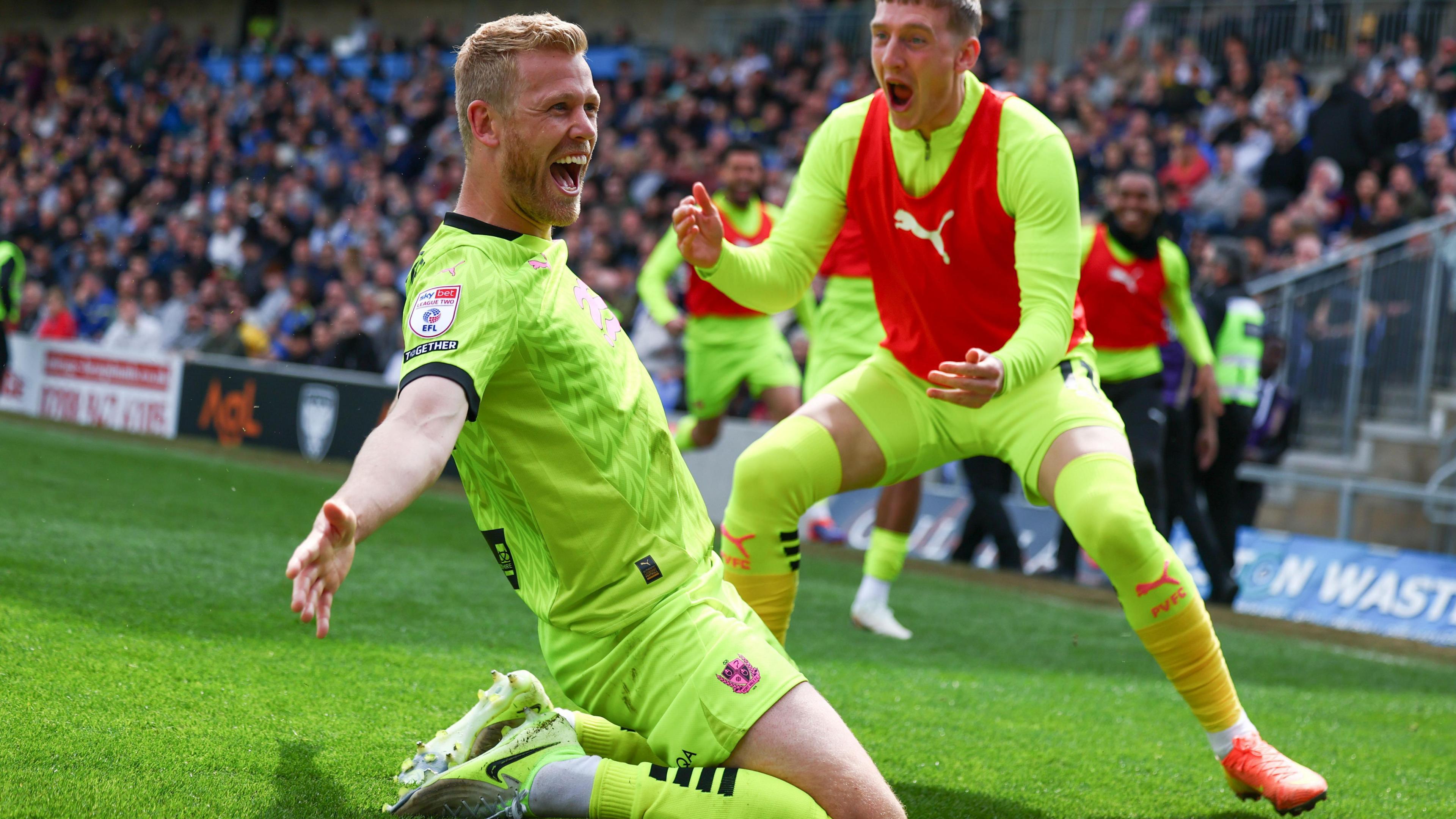 Jayden Stockley slides on his knees in celebration after scoring against Wimbledon in a win that clinched Port Vale's promotion to League One