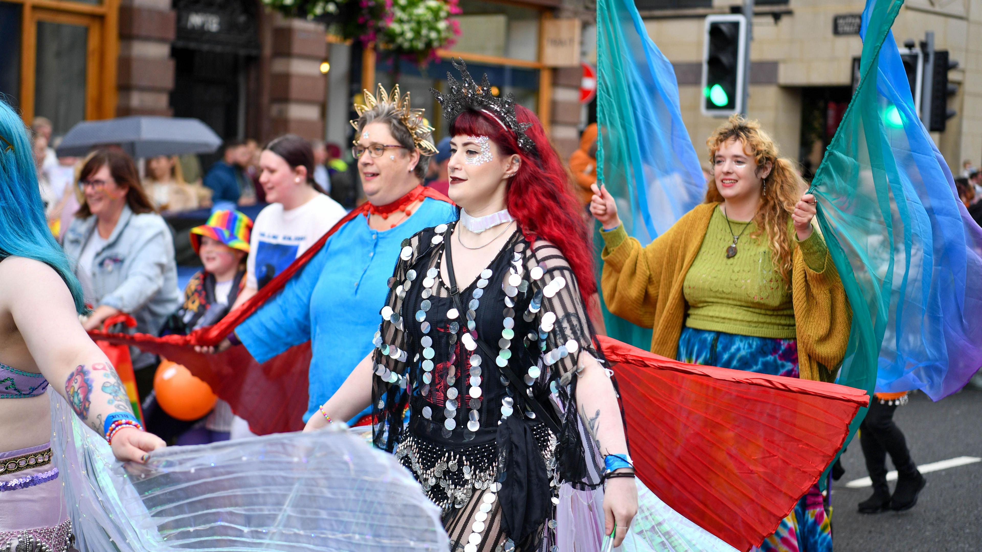 A crowd of people are in a parade. They're dressed in in various bright colours.