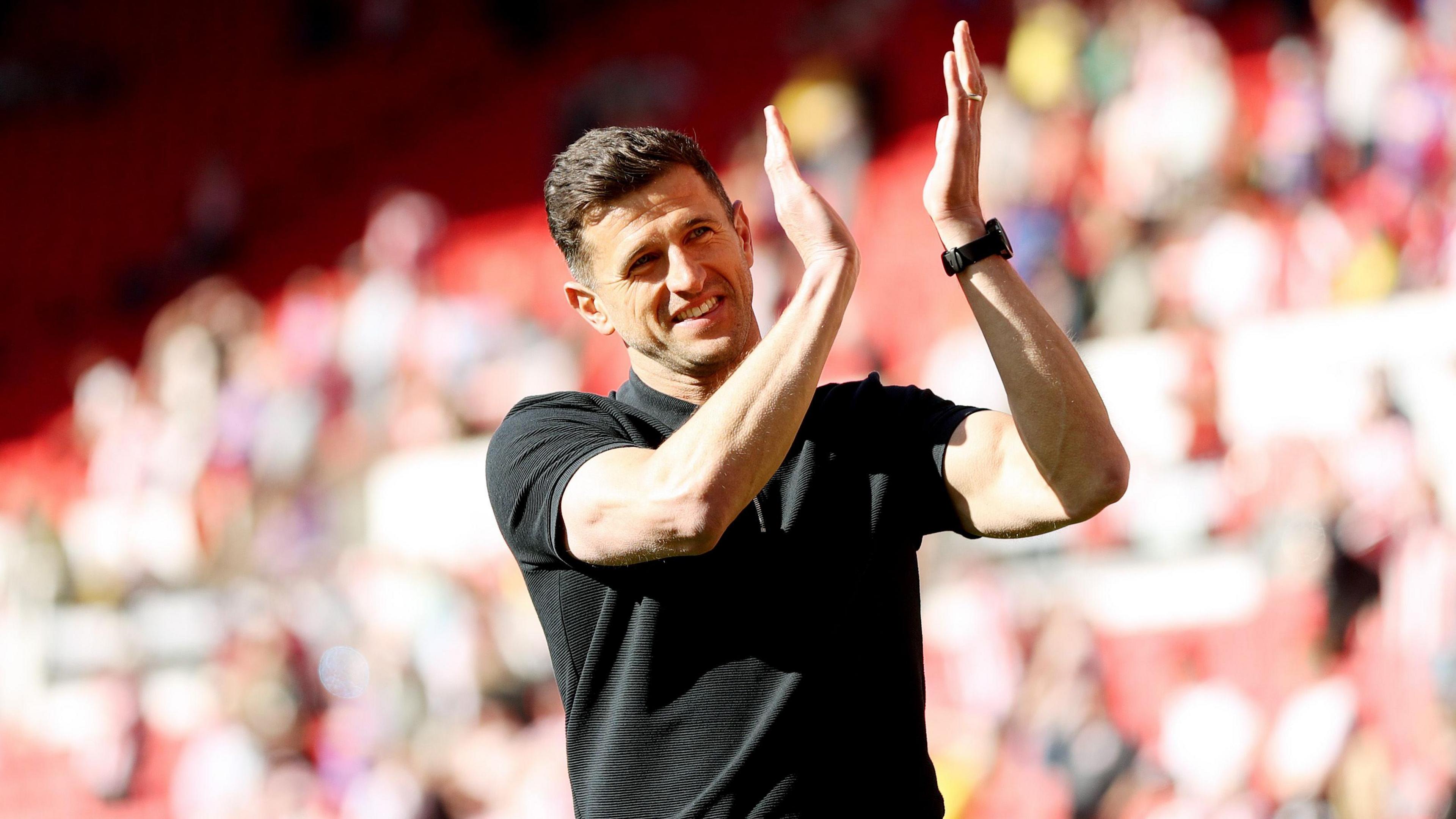 Portsmouth manager John Mousinho smiles as he applauds the fans at full time 
