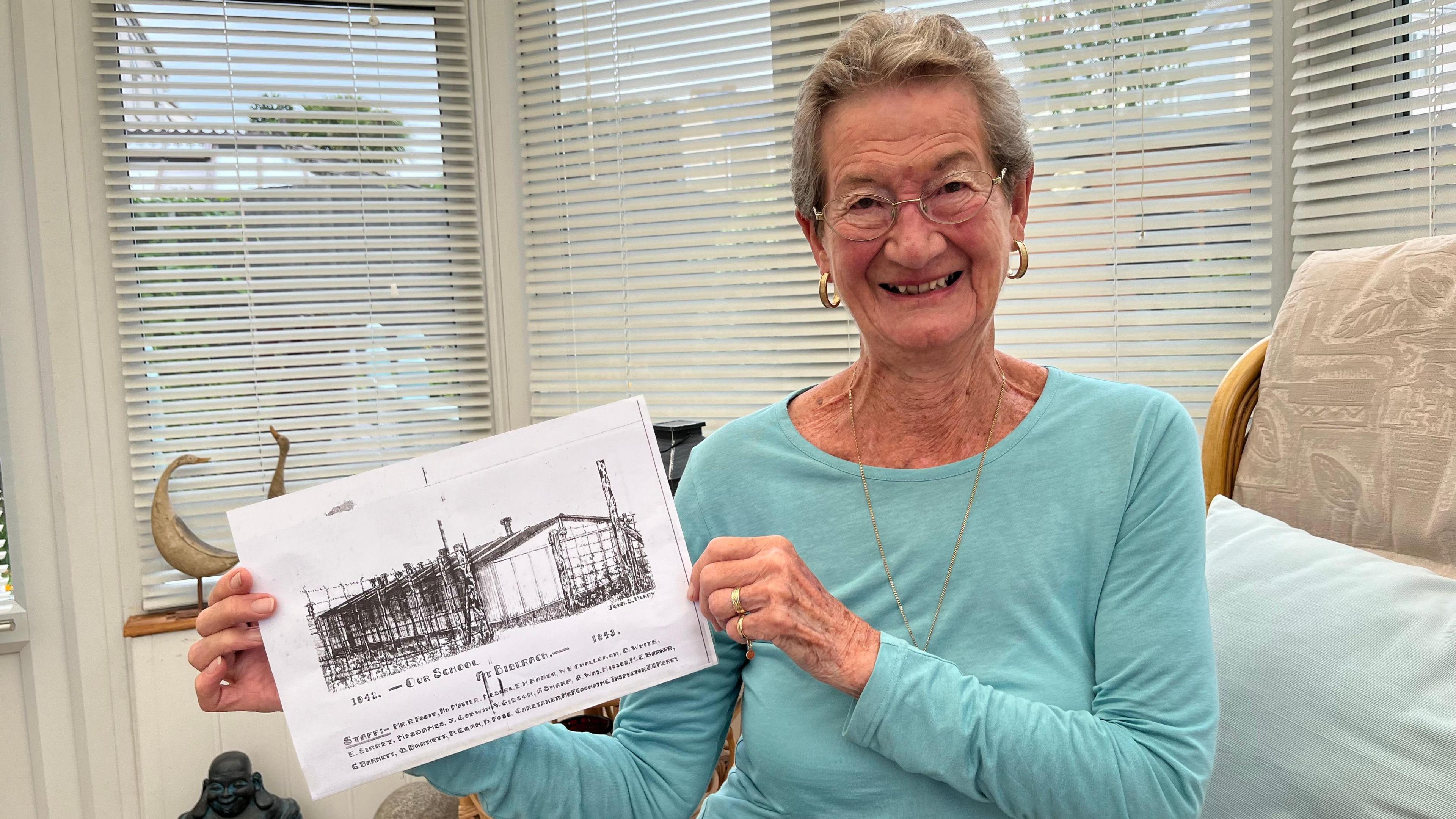 Jill Chubb holding a drawing of the school at Biberach camp