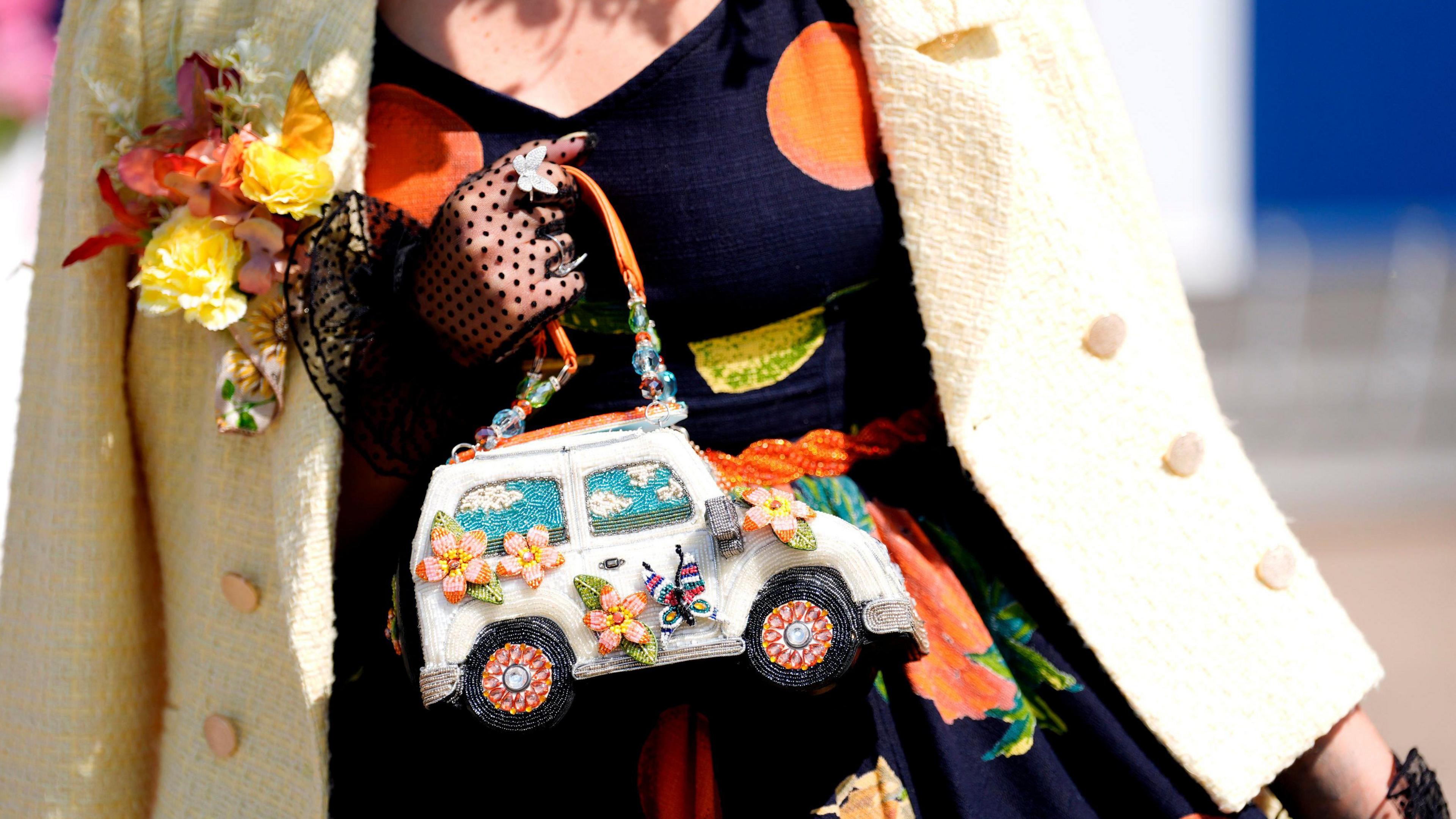 A woman holding a woollen handbag in the shape of a van.