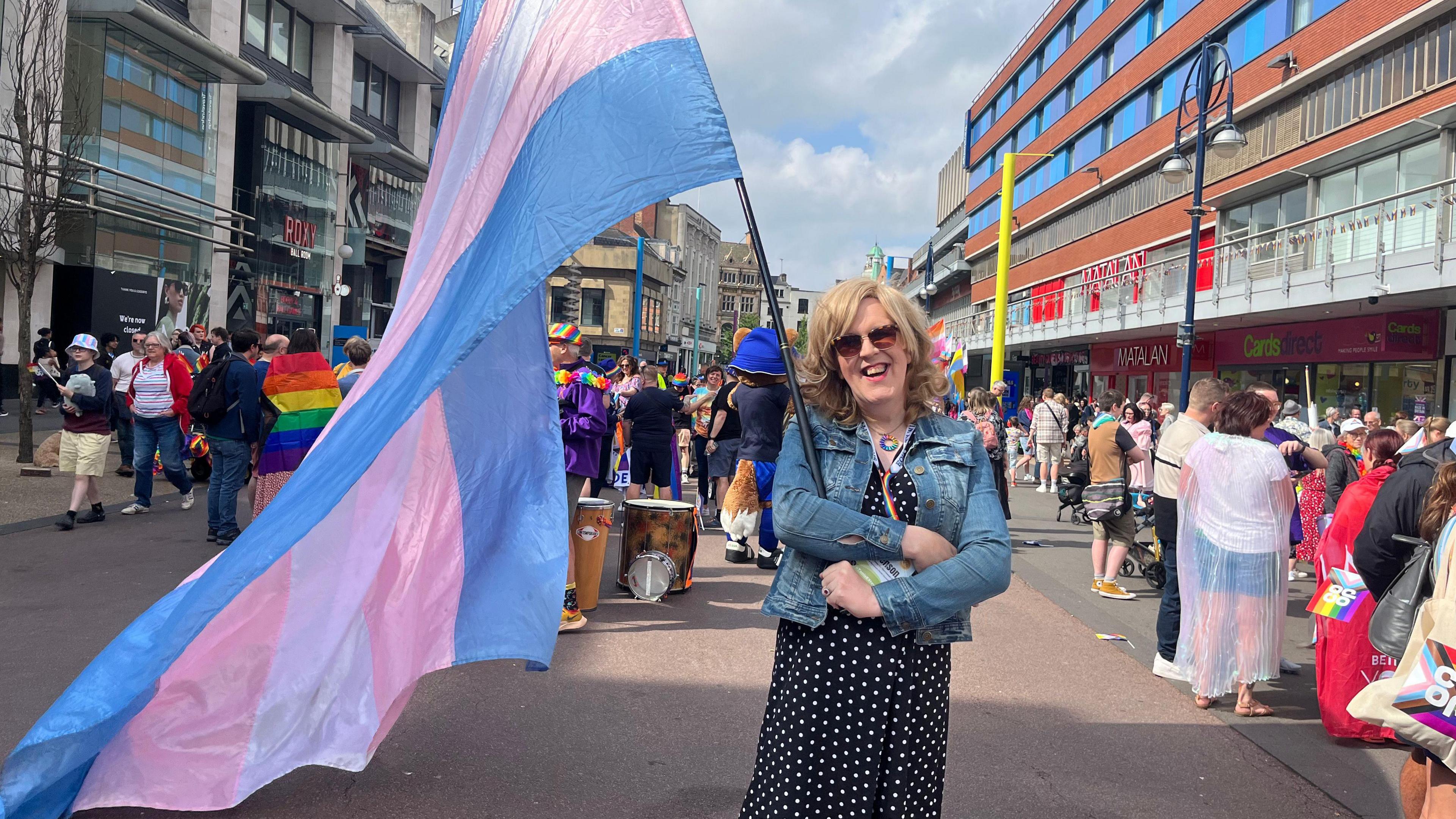 A Leicester Pride attendee carrying a large transgender pride flag