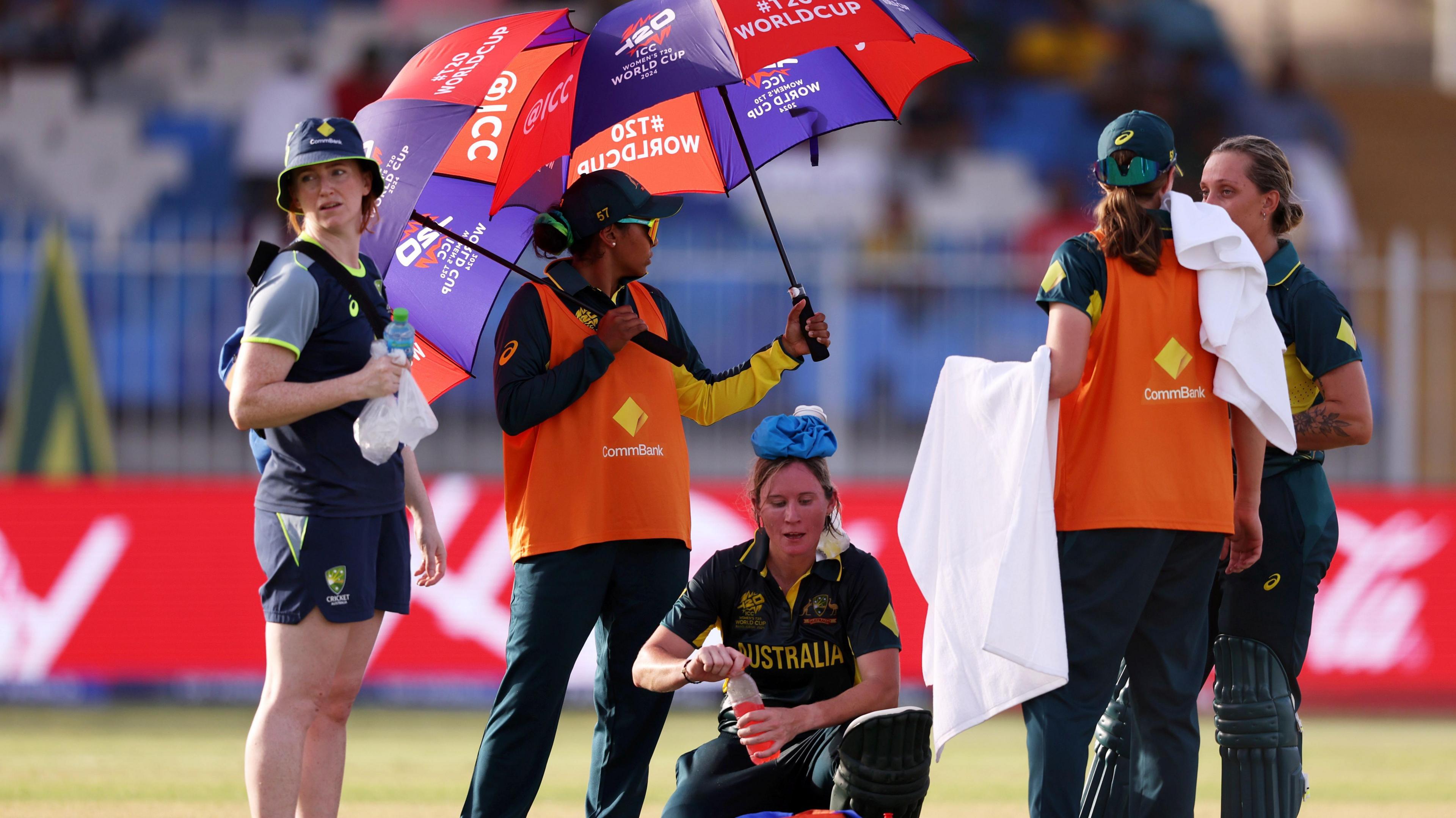 Australia's Beth Mooney, with an ice pack on her head, shelters from the sun under an umbrella during a T20 World Cup match in the United Arab Emirates in 2024