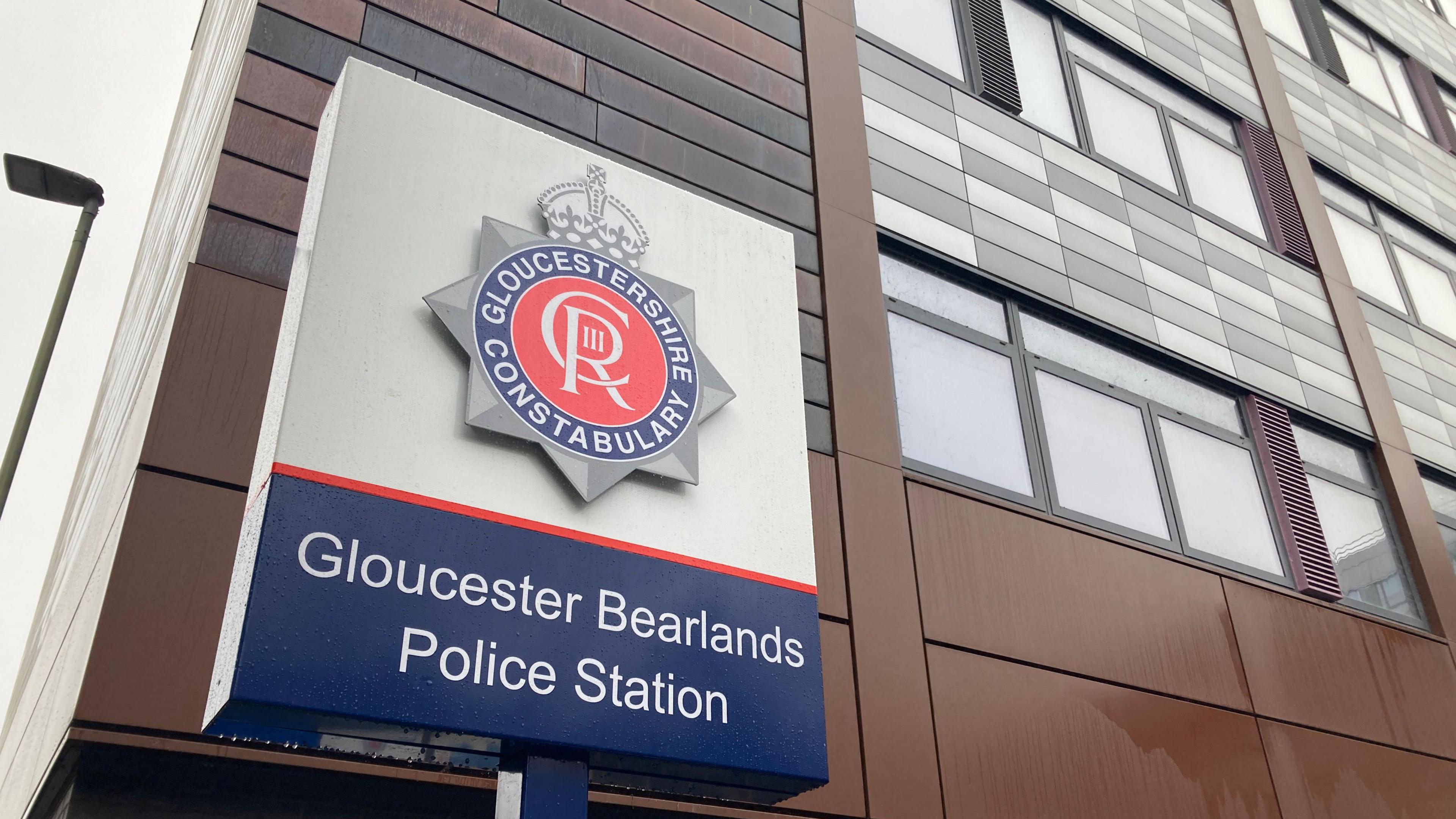 A outside Gloucester Bearlands station featuring the Gloucestershire constabulary logo which is circular and a mixture of red and blue with white lettering