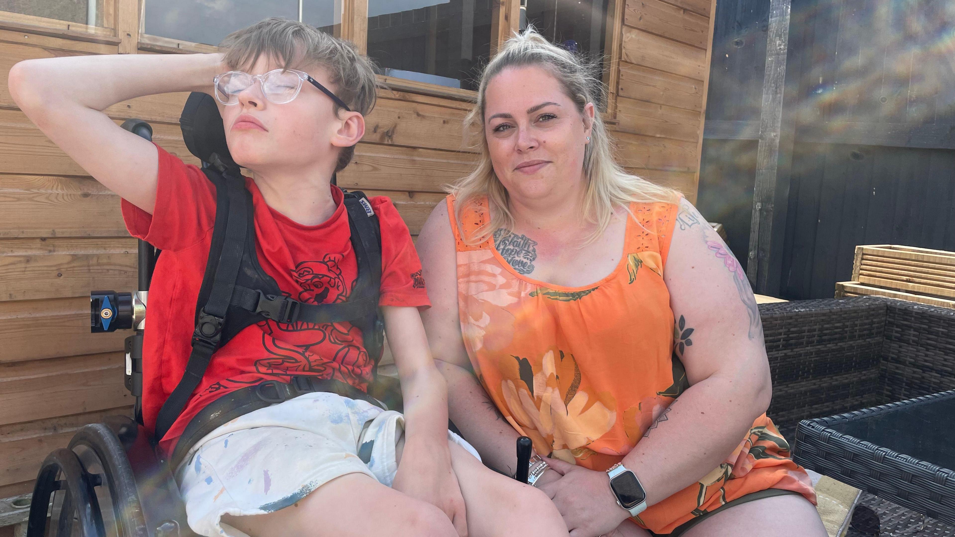 A mother sits next to her son who uses a wheelchair