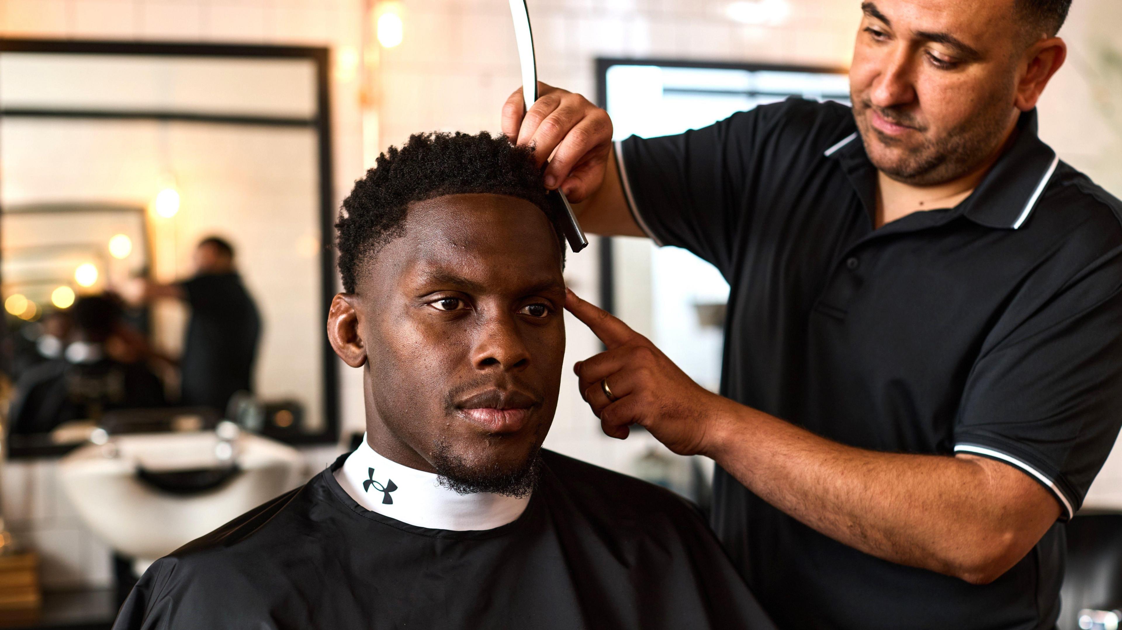 Maro Itoje having his haircut by his long-time barber Moussa