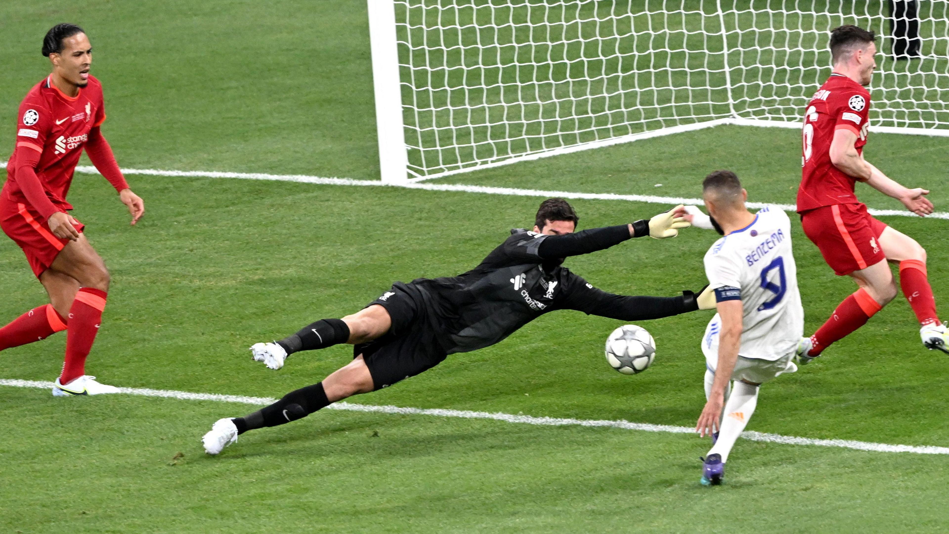 Liverpool on the defensive in the 2022 Uefa Champions League final in Paris. The Liverpool goalkeeper Alisson is photographed diving full length to his left to save a shot on goal from Real Madrid striker Karim Benzema.