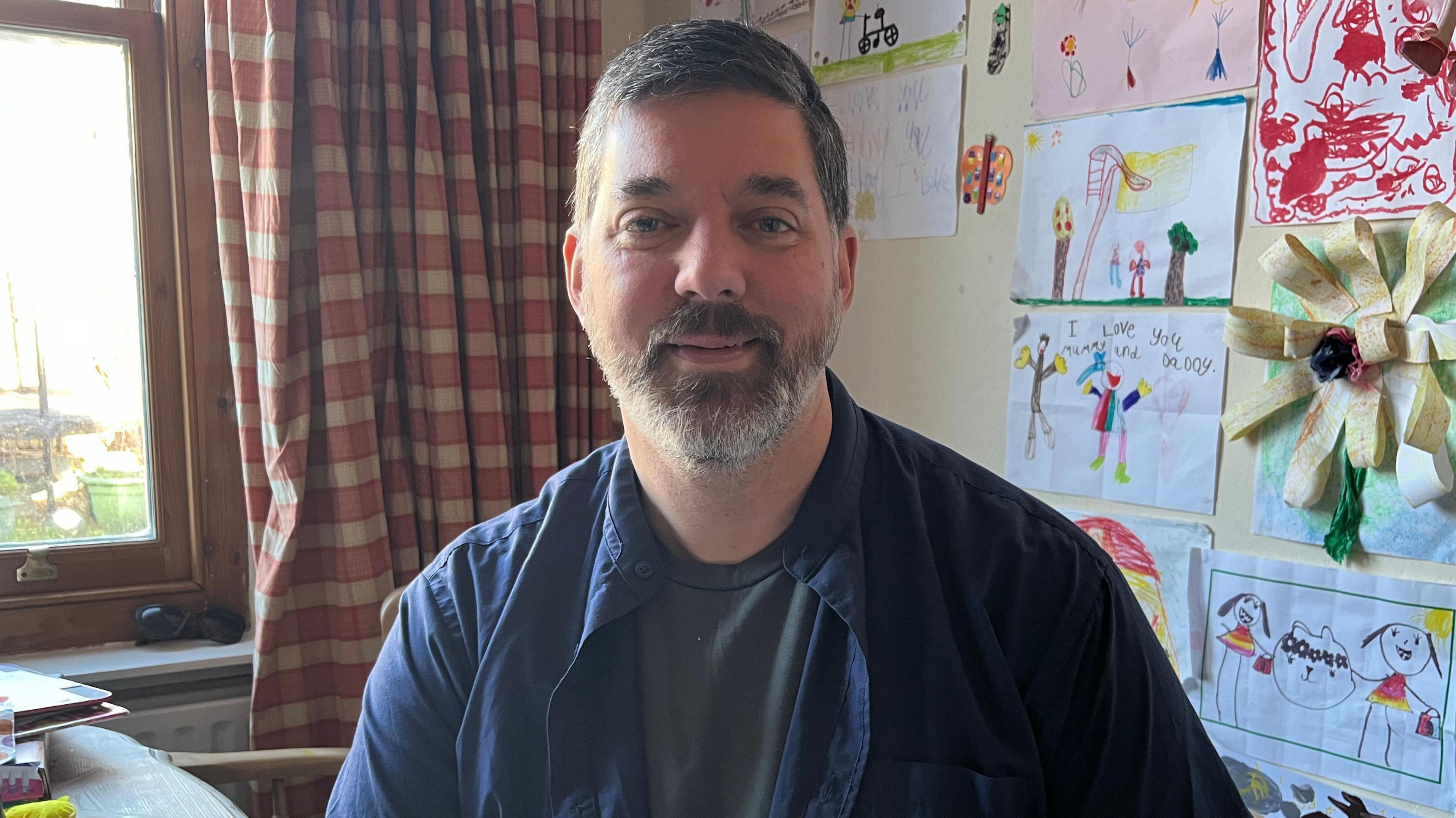 Private renter Andy Coley at home. Drawings by his children are on the wall behind him.