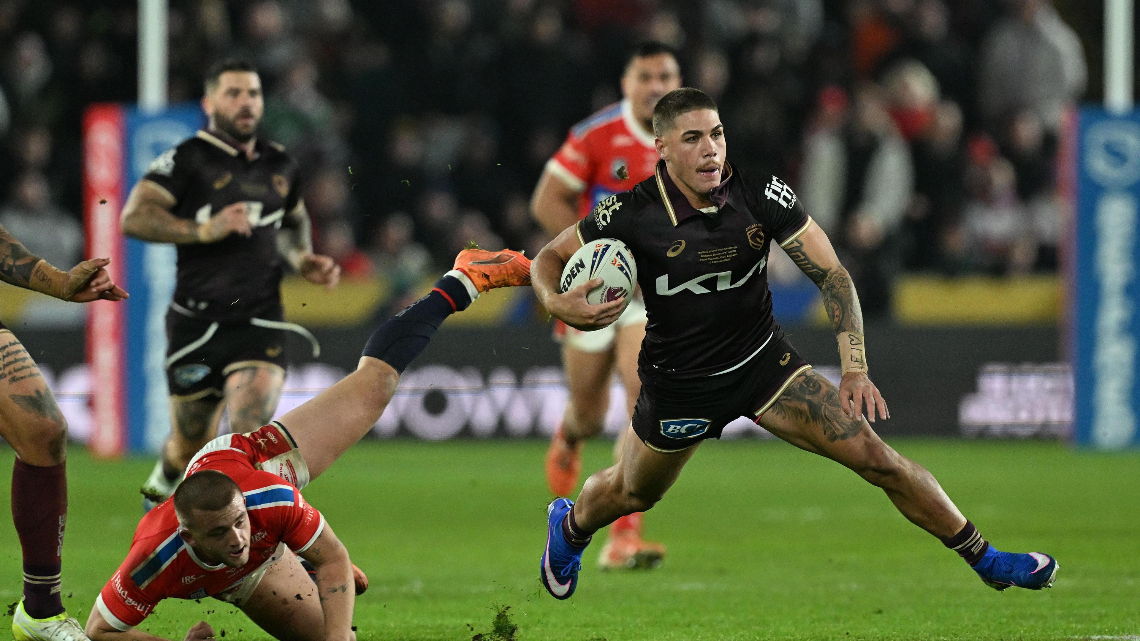 Reece Walsh (right) evades a tackle from Mikey Lewis (left)