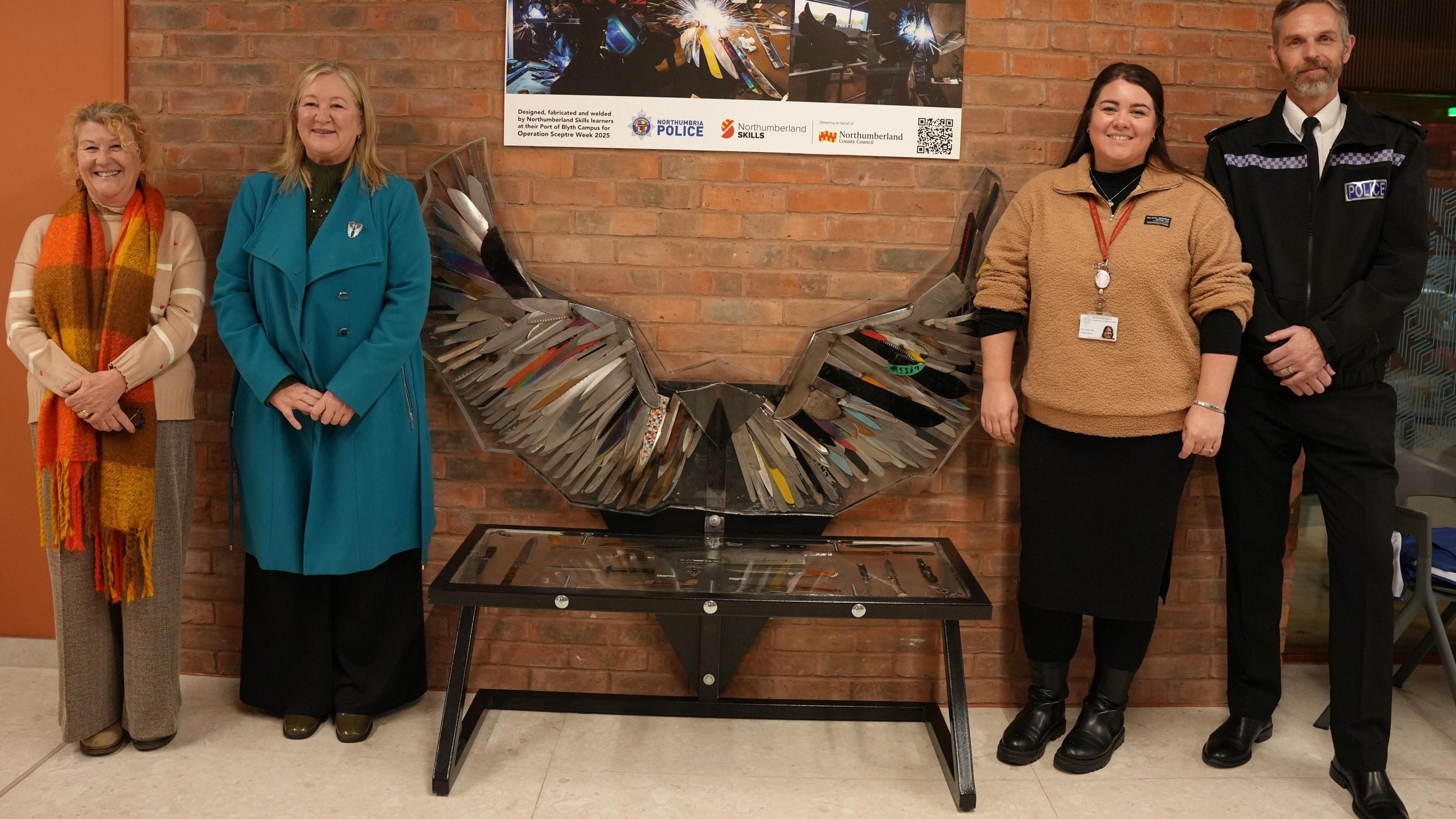 The bench is visible in the centre of the image. There are four people in the image (two standing either side of the bench). From left to right, there is Susan Dungworth, Alison Madgin and her daughter Carly Barrett of Samantha’s Legacy (who are standing closest to either side of the bench) and then Superintendent Scott Cowie.
