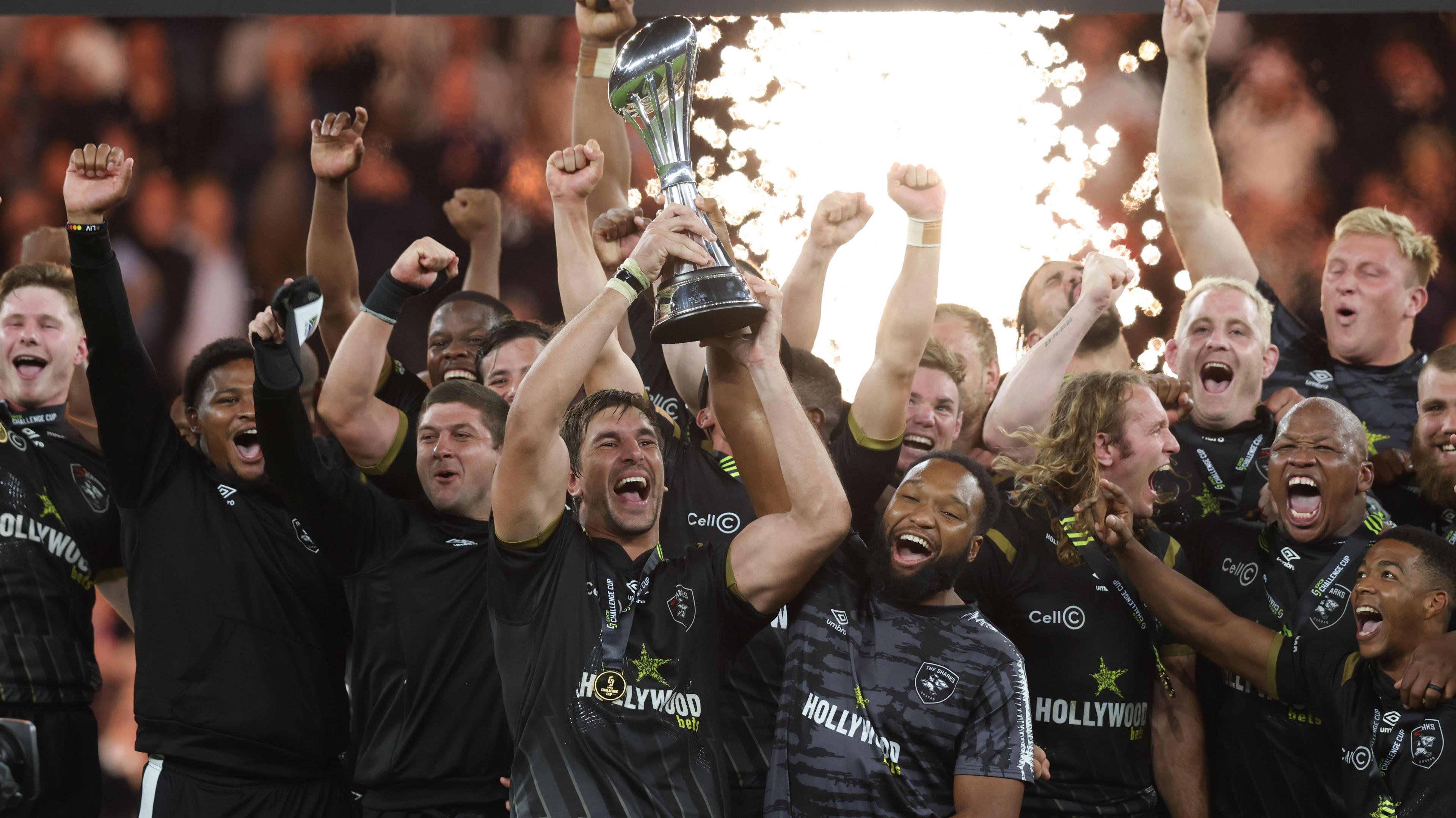 Sharks players celebrate with the trophy on the podium