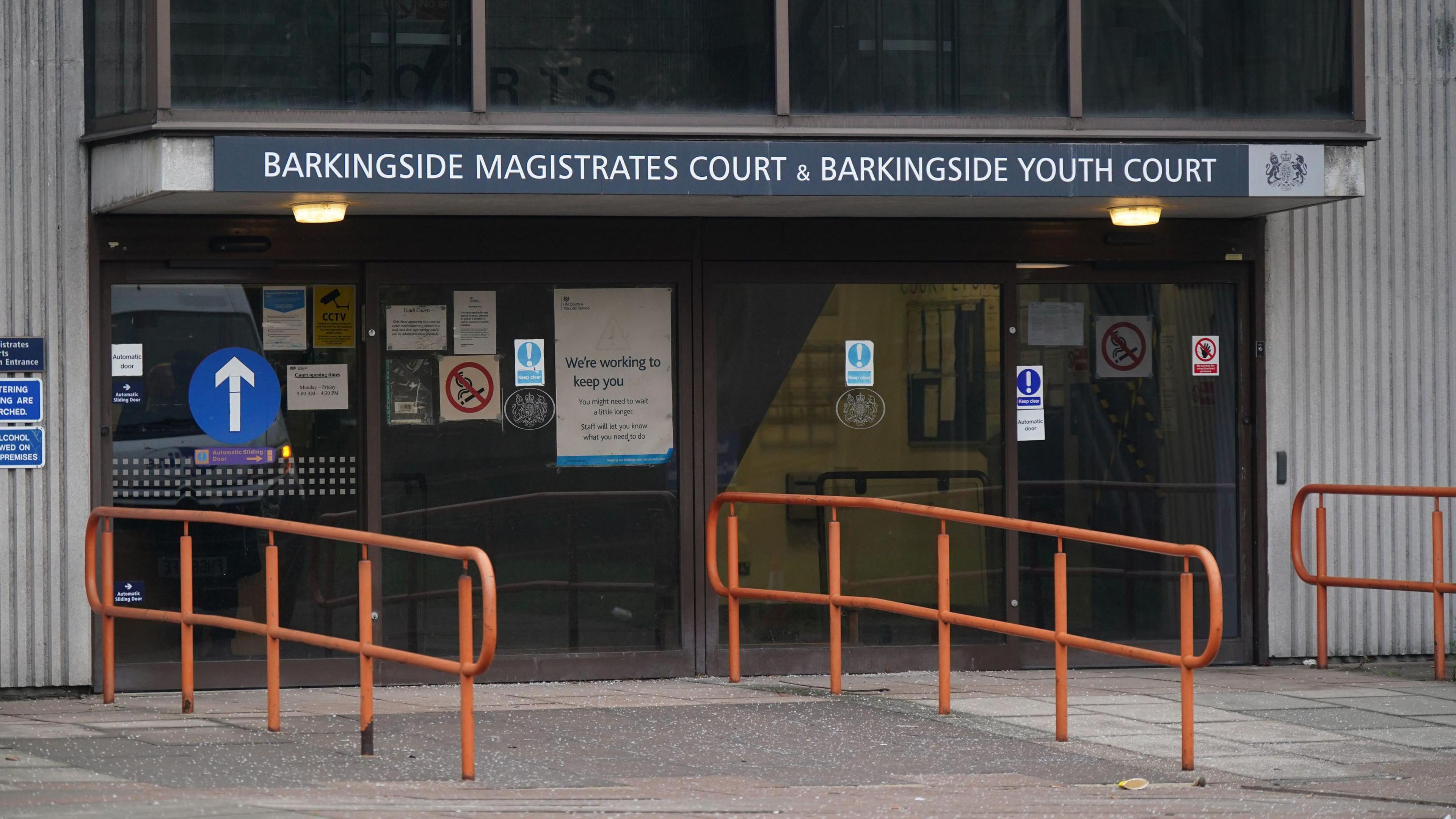 Exterior view of Barkingside Magistrates Court with orange railings, a concrete ramp and grey and white sign