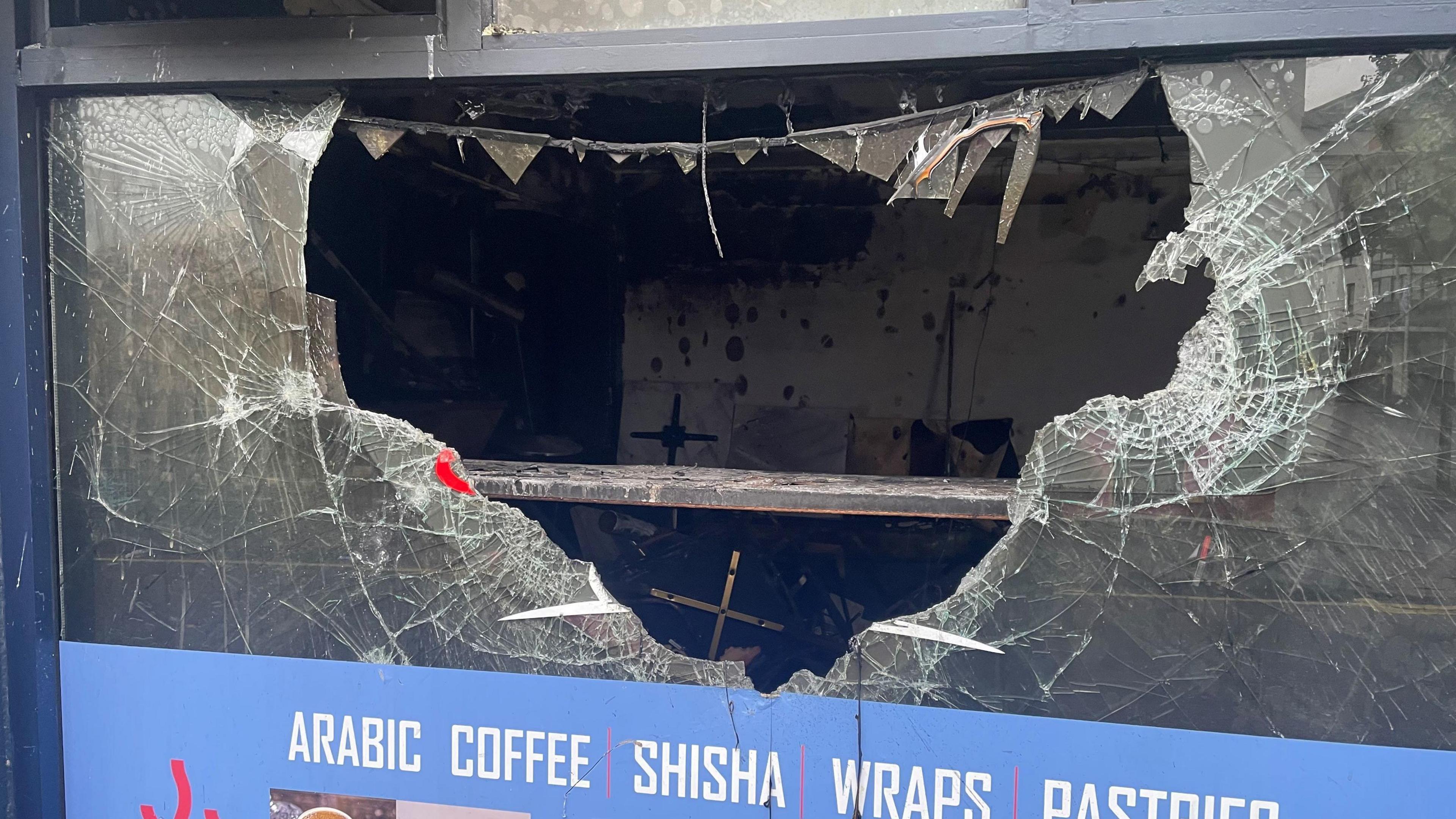 Image shows Bash Cafe with a hole in the window 