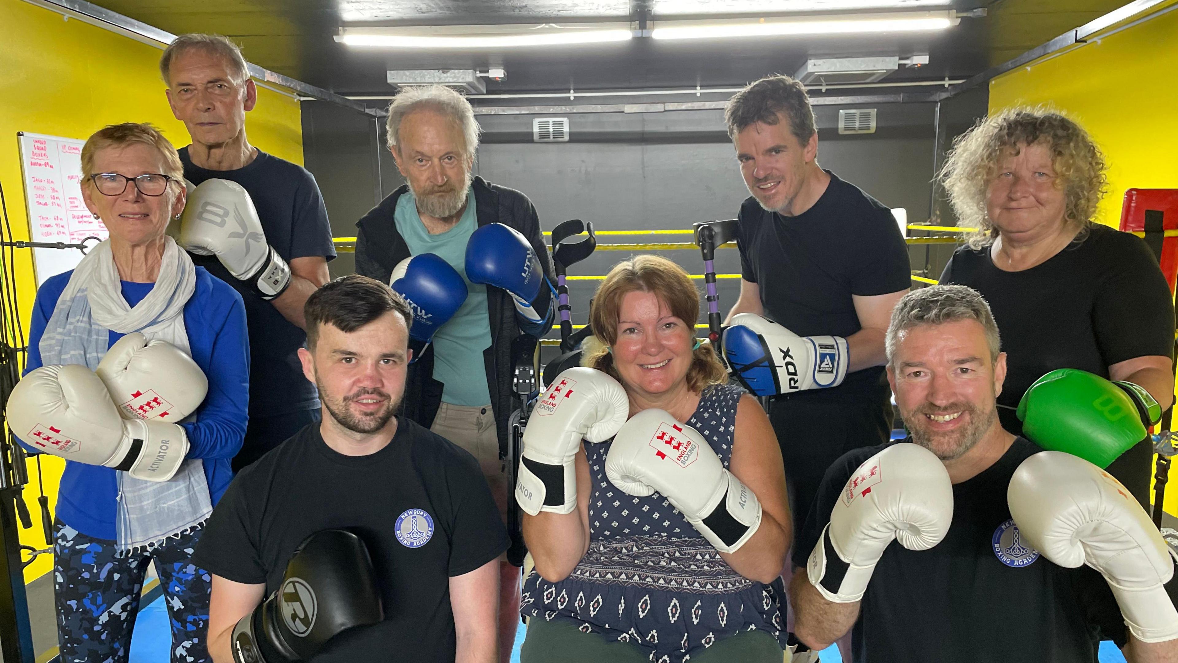 Eight coaches and members of the Parky Blinders in the gym. They are all wearing boxing gloves. 