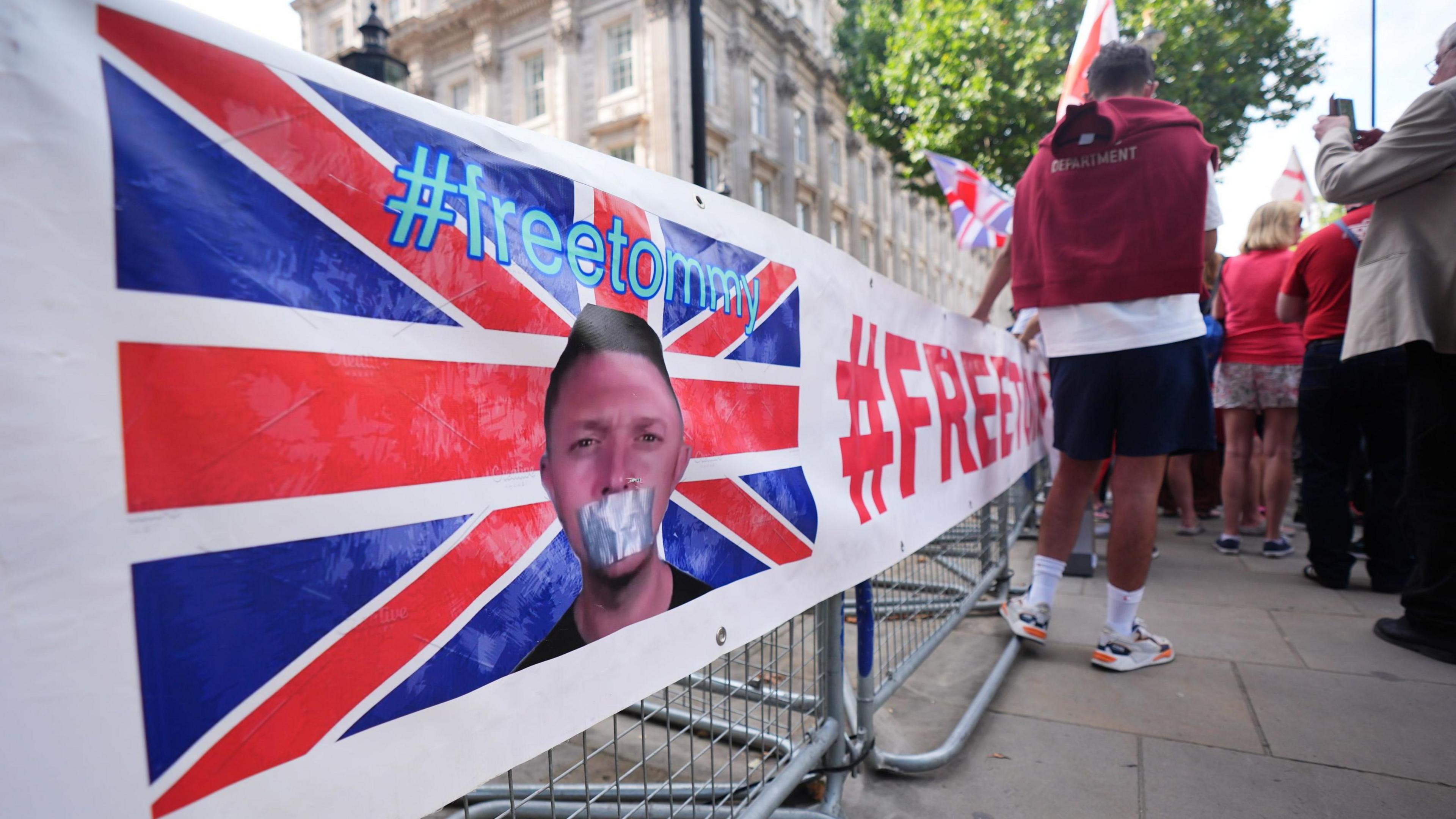 A campaign banner showing a picture of Tommy Robinson with tape over his mouth