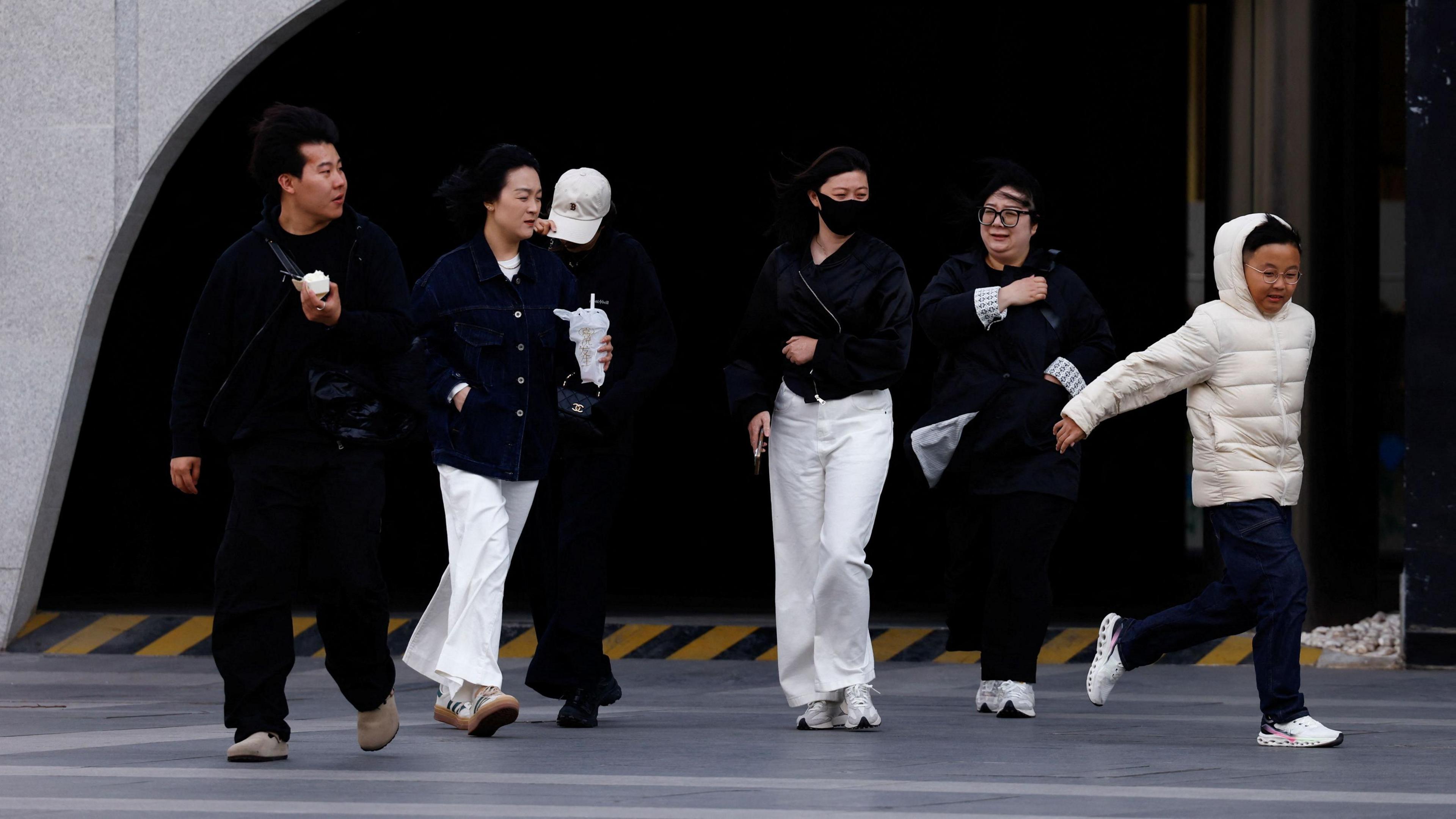 People walk amid strong winds in Beijing, China