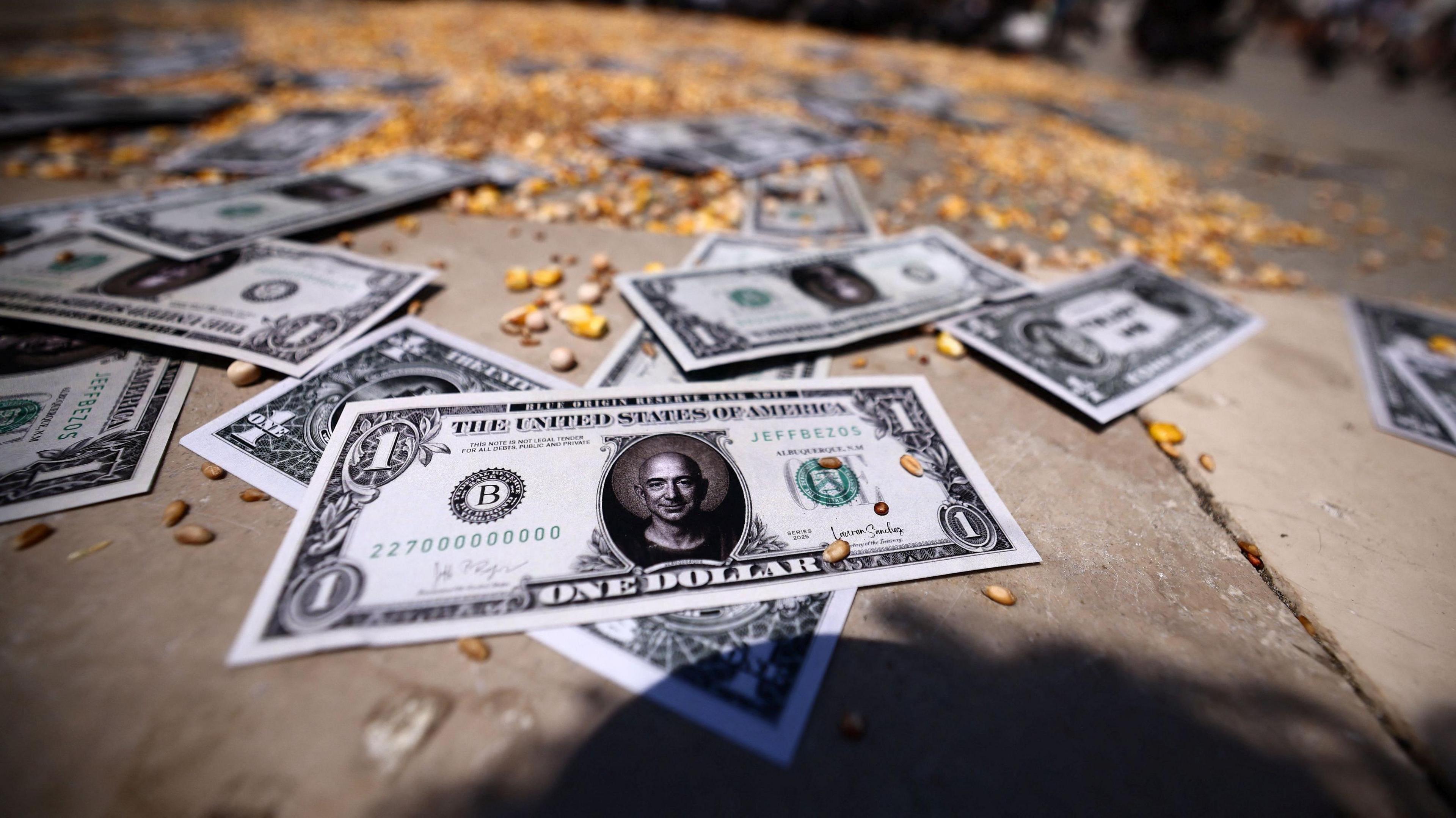 Fake one-dollar notes with Amazon founder Jeff Bezos' face on them are seen on the street in St. Mark's Square on 24 June, 2025