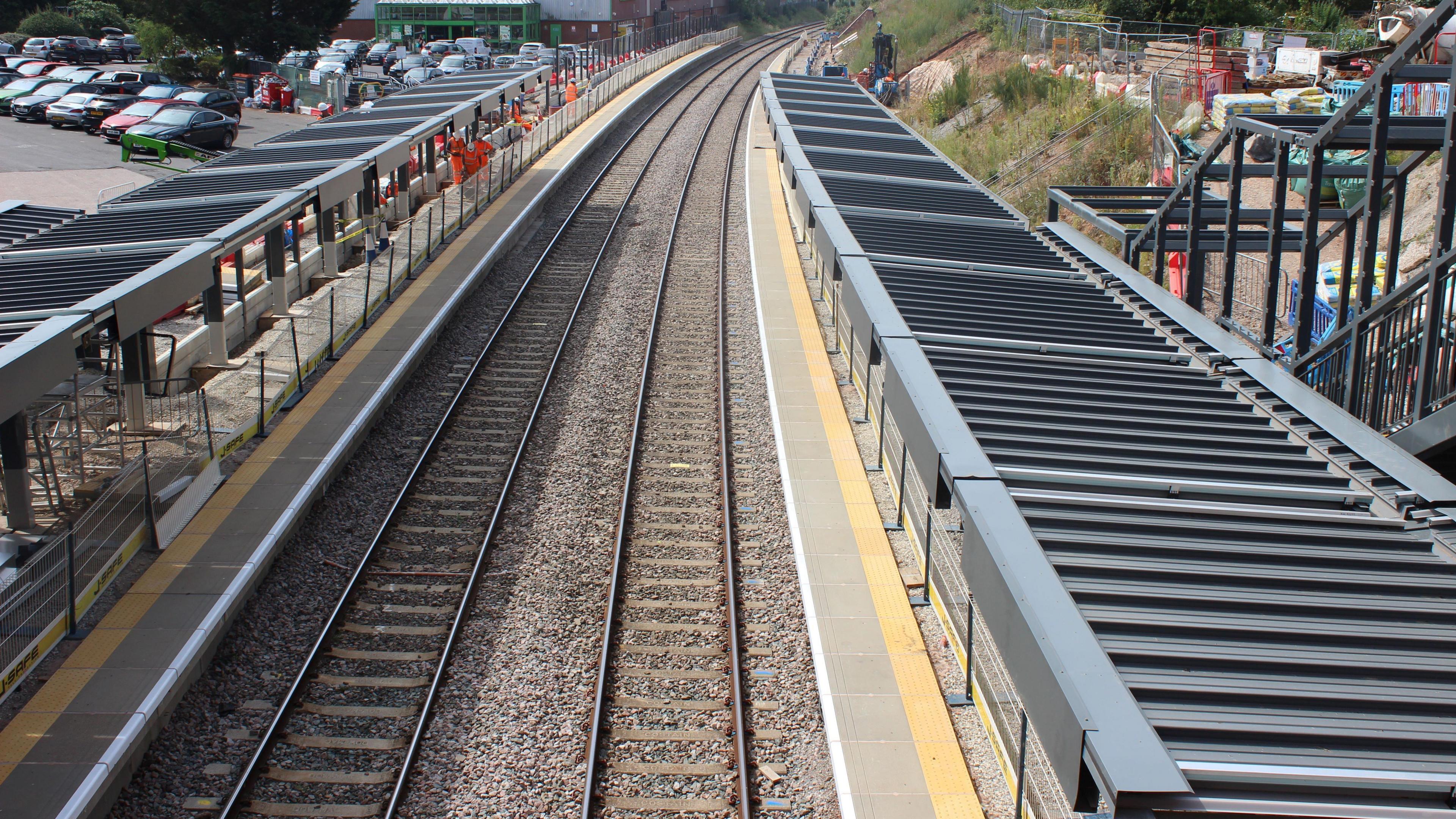 An aerial shot of Kings Heath station, showing railings and canopies. Cars can be seen in the background.