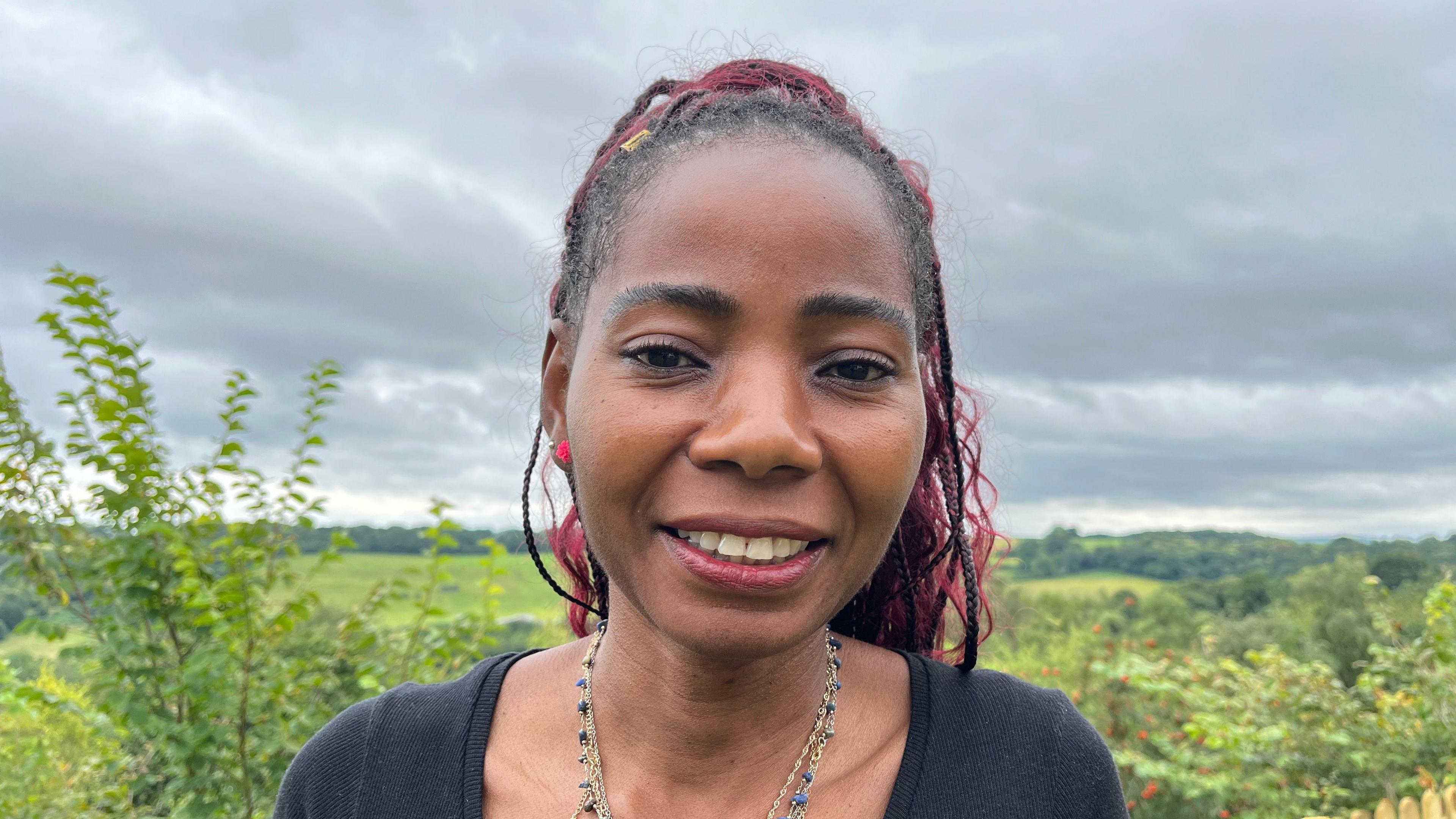  Rose Ayikpah with red braids, a black top and a necklace