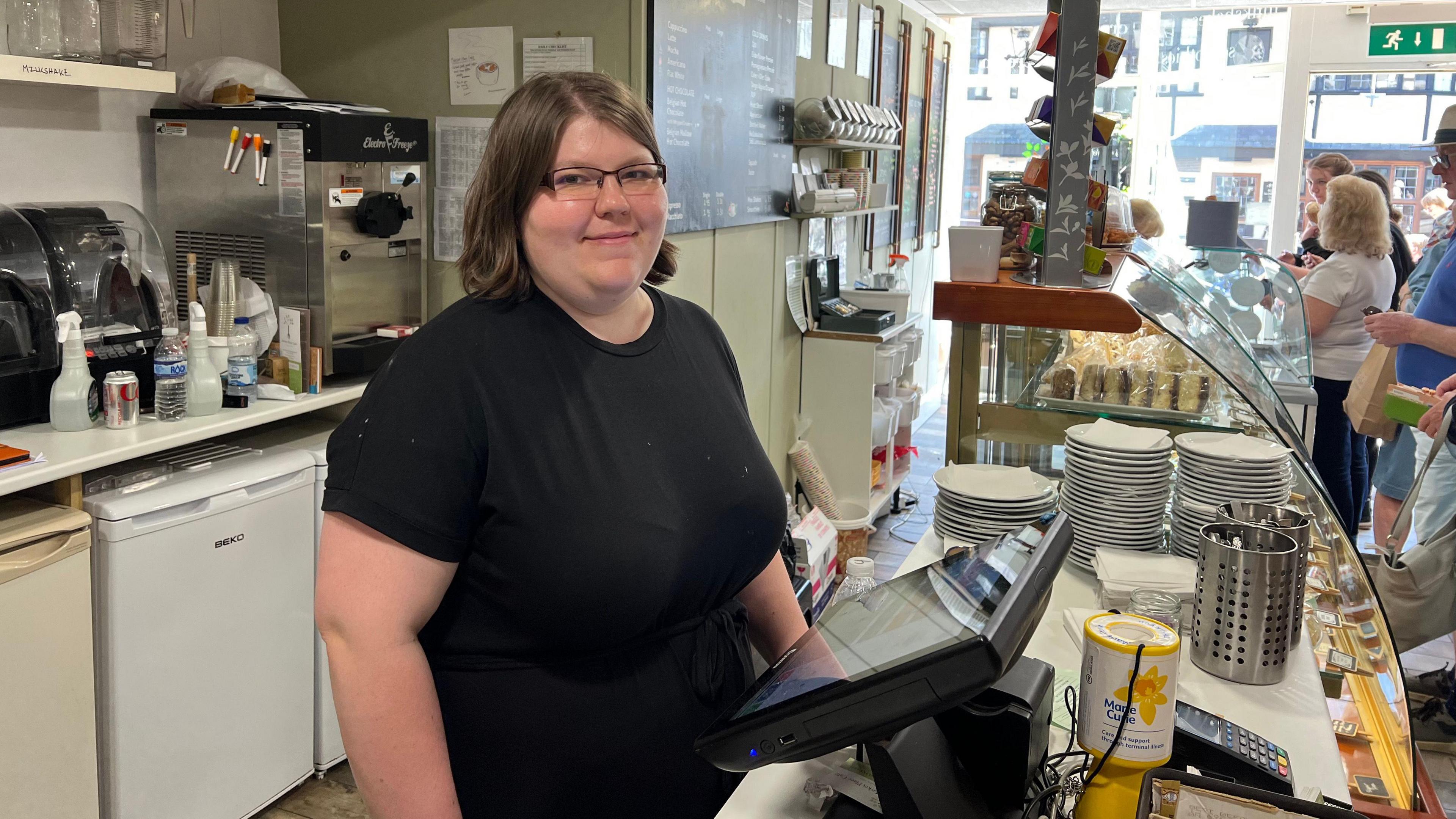 Jade at the Market Place Cafe in Wells, standing behind the till