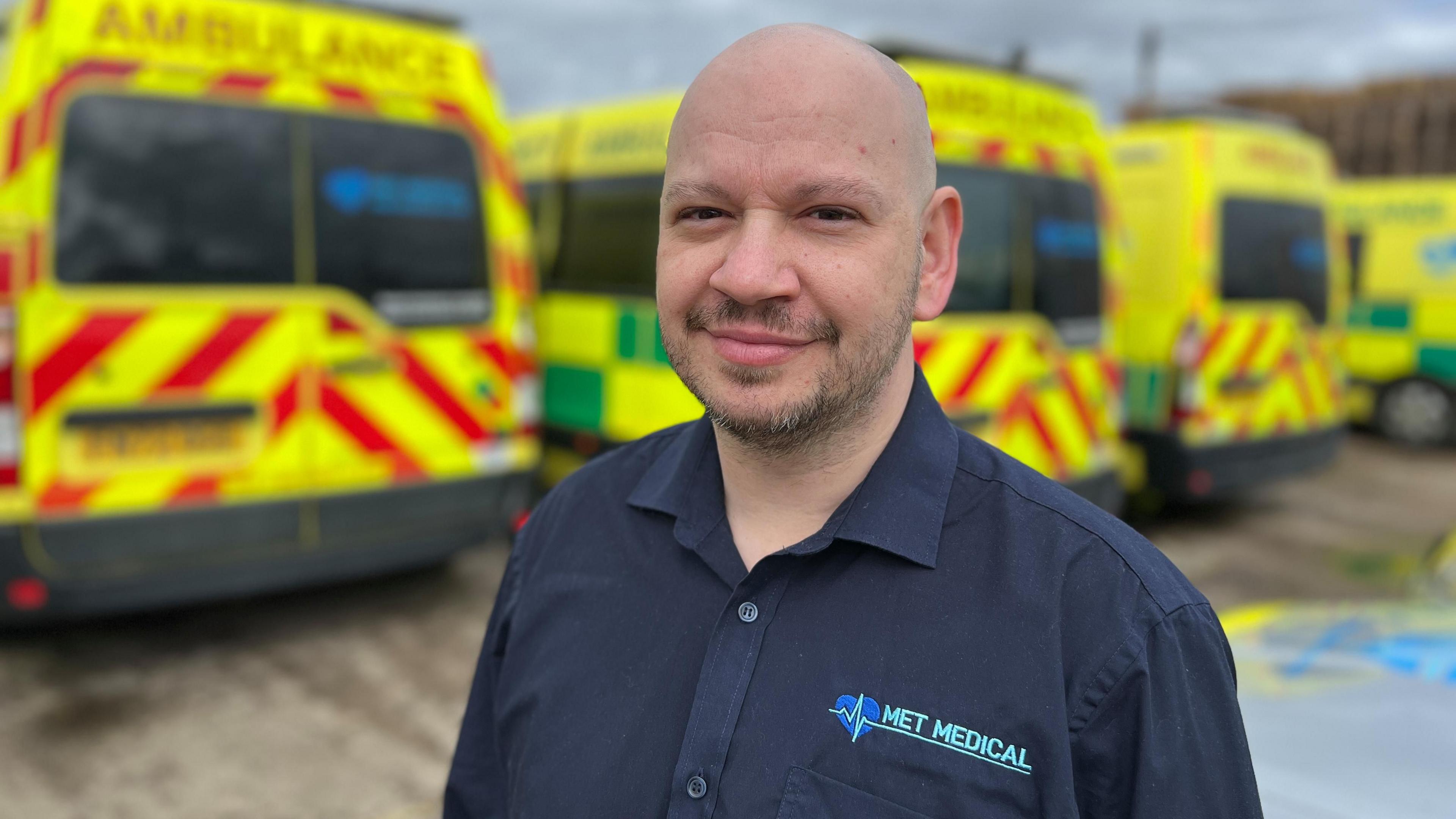 Dave Hawkins standing in front of some MET Medical ambulances